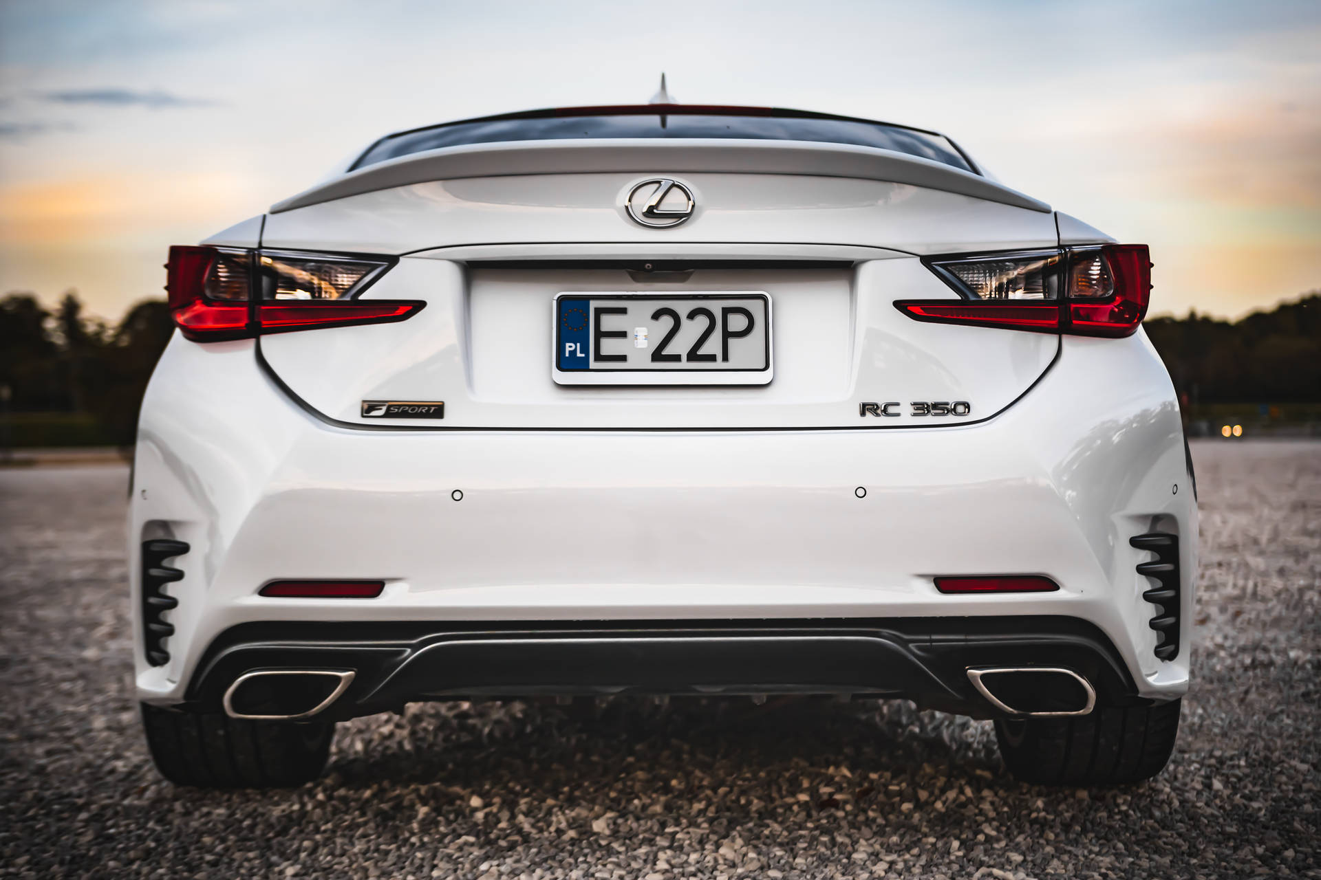 白色Lexus RC 350 F Sport在日落時分碎石路上的後視圖。