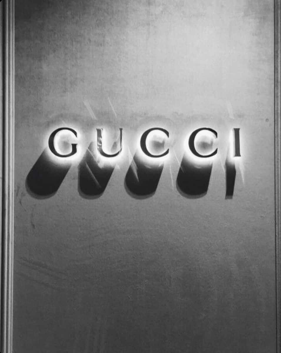 Gucci 標誌喺有紋理嘅金屬背景上發光。