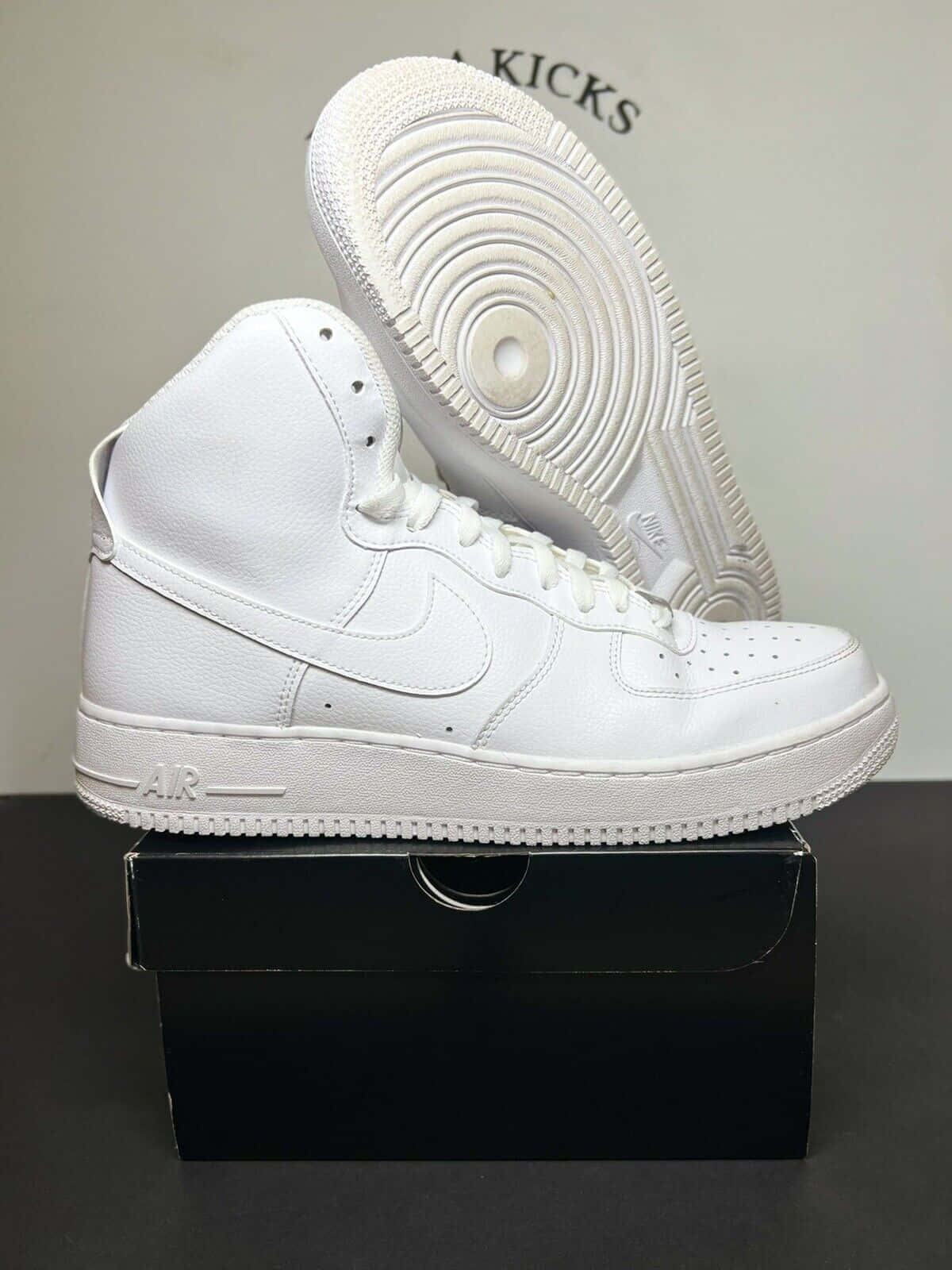 白色Nike Air Force 1高筒運動鞋放在黑色鞋盒上，鞋底可見。