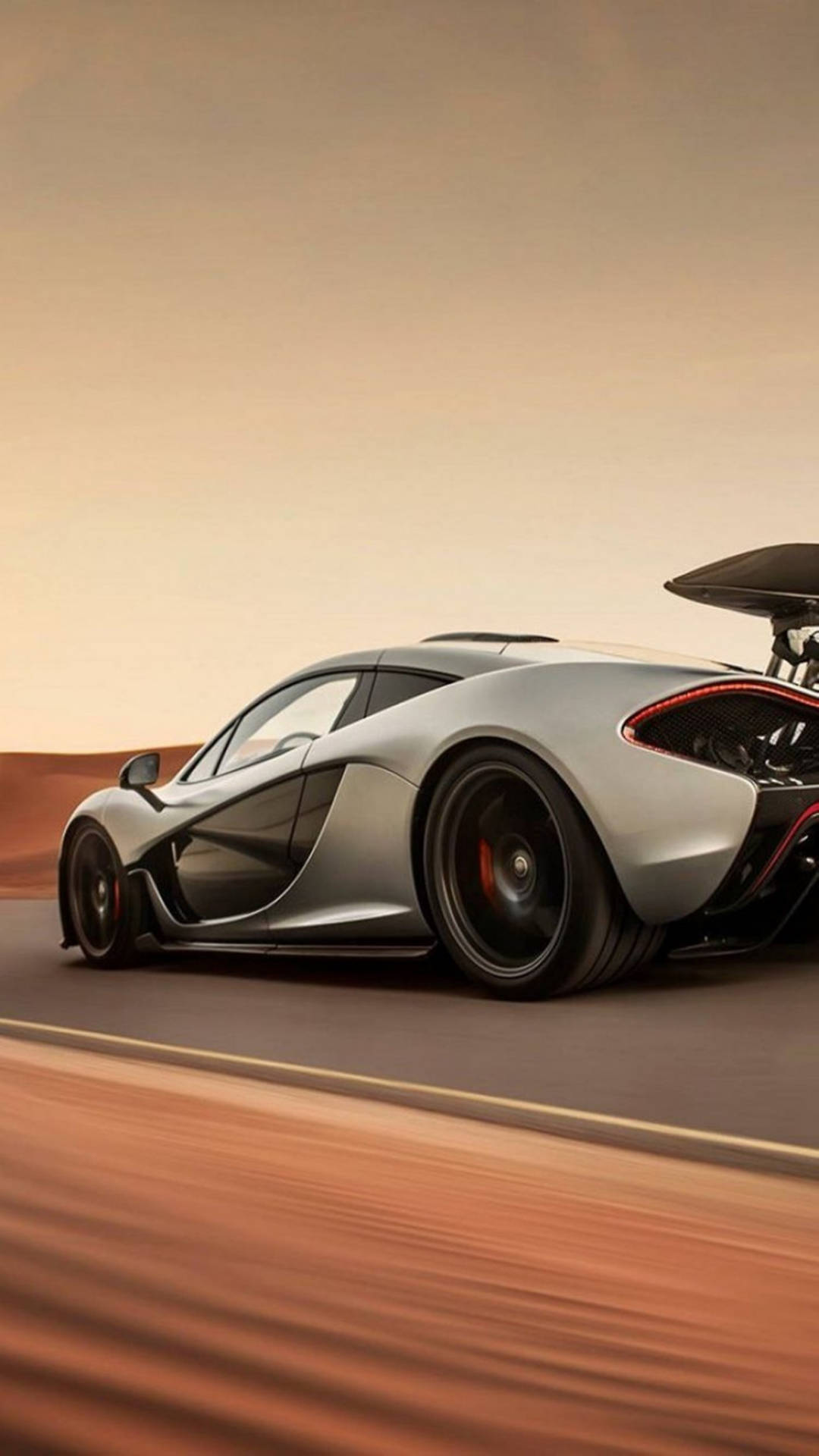 銀色McLaren P1在沙漠公路上奔馳，日落時分