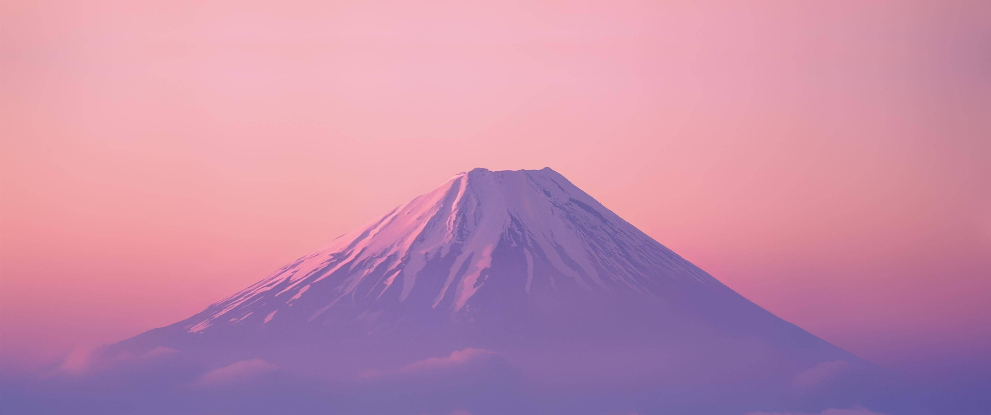 Mountain 桌布 壁紙 — 白雪覆蓋的富士山在柔和的粉紅色和紫色暮色天空下，穿過薄霧雄偉地聳立。