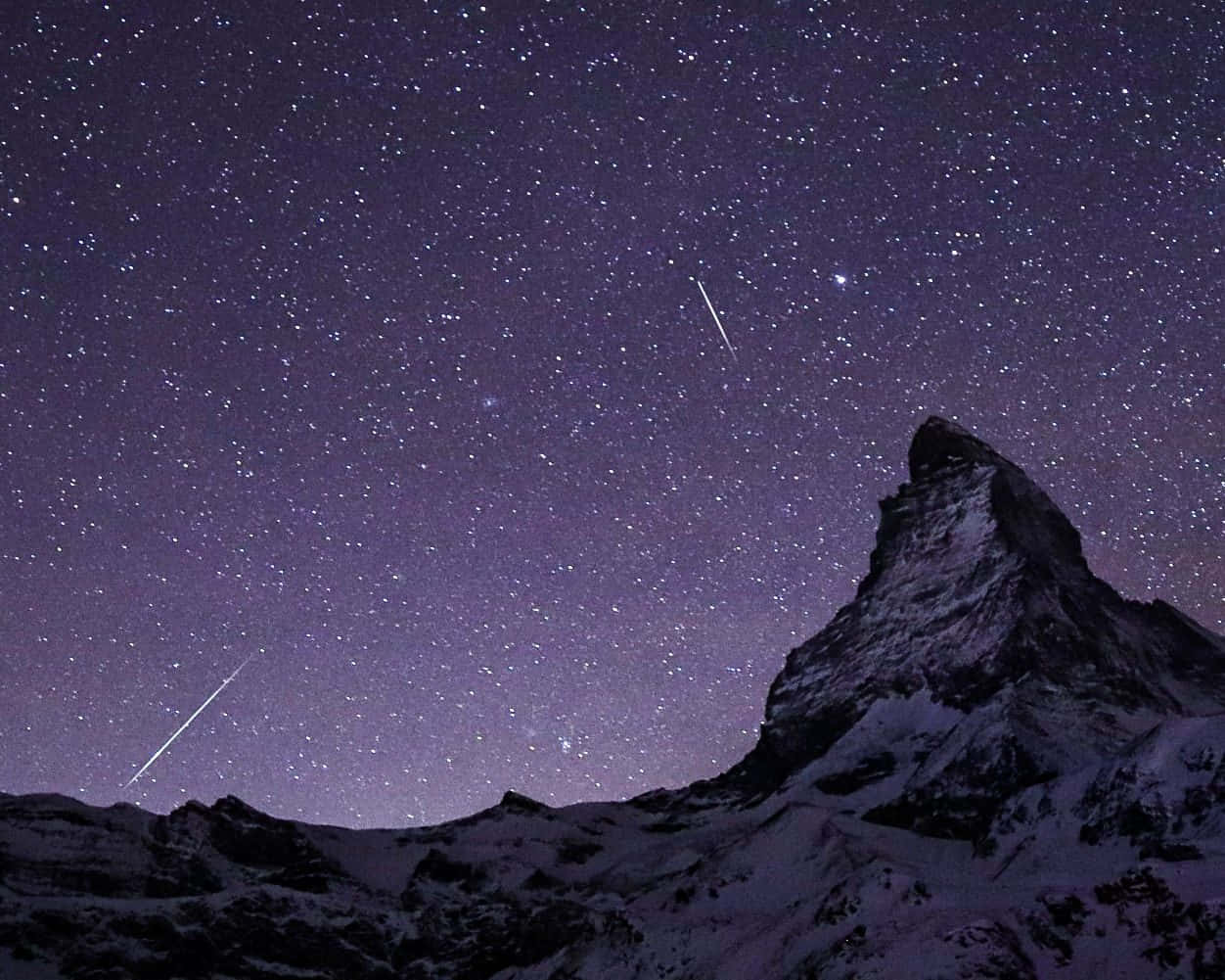 Aesthetic Night Sky 桌布 壁紙 — 白雪覆蓋的山峰在佈滿星星的紫色夜空下聳立，夜空中有兩顆明亮的流星劃過。