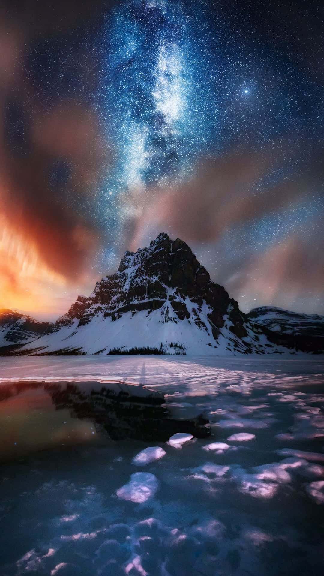 Captivating 桌布 壁紙 — 白雪覆蓋的山峰在充滿活力的星空下倒映，銀河在冰凍的湖面上拱起。
