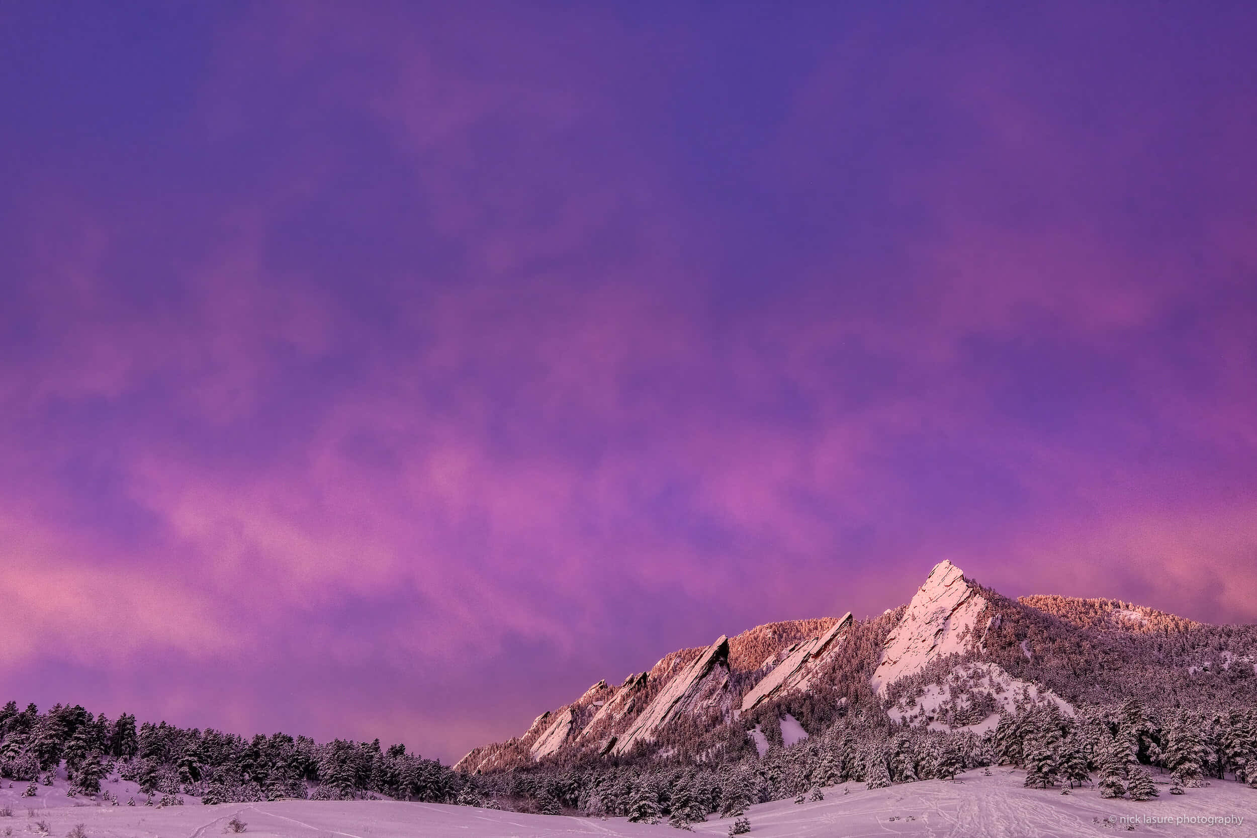 Purple Mountains Majesty 桌布 壁紙 — 白雪覆蓋的山峰在充滿活力的紫色和粉紅色暮色天空下閃耀，伴隨著柔軟的雲朵。