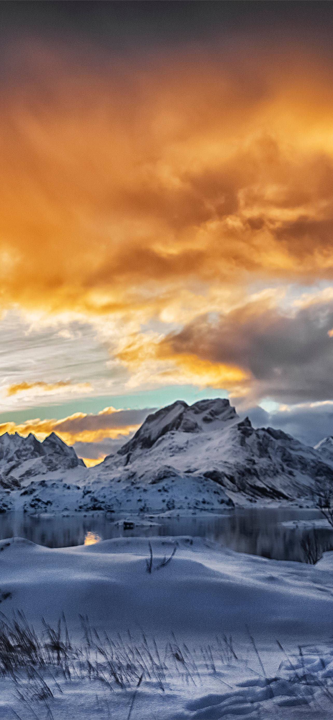 Svalbard 桌布 壁紙 — 白雪覆蓋的山峰在平靜的湖面上倒映，天空是火熱的橙色日落。
