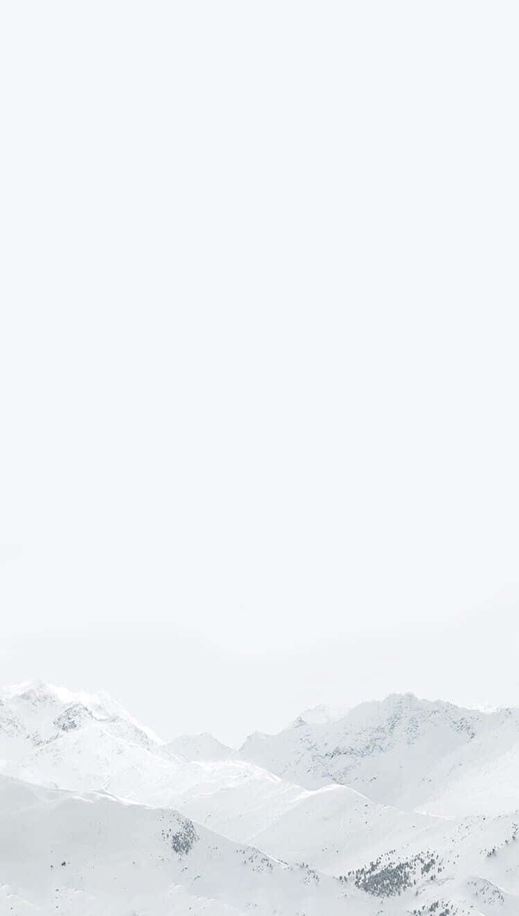 白色 iPhone 桌布 壁紙 — 白雪覆蓋的山峰在極簡冬季景觀中逐漸融入朦朧的白色天空。