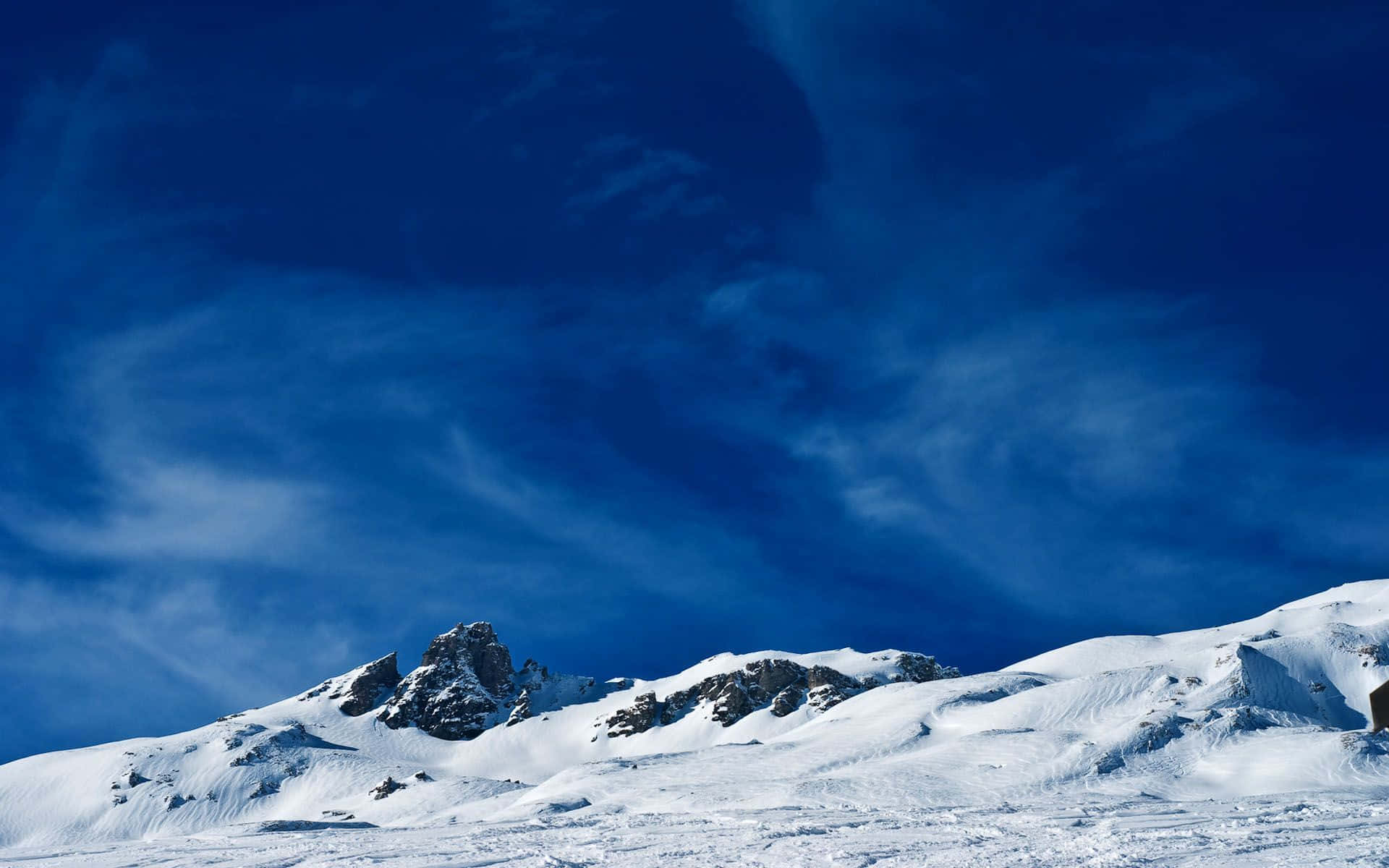 Winter Blues 桌布 壁紙 — 白雪覆蓋的山峰在深藍色天空和縷縷薄雲的映襯下巍然聳立。