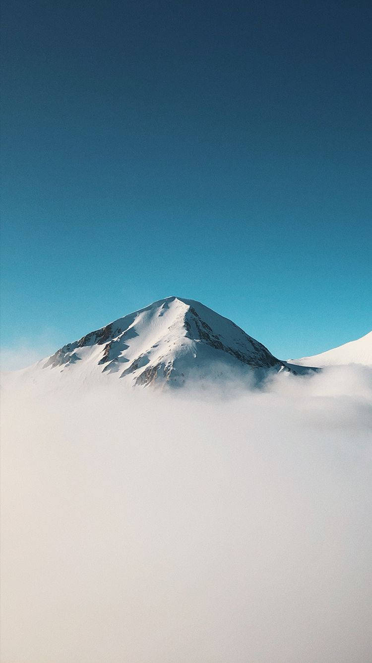 Mountain 桌布 壁紙 — 白雪覆蓋的山峰在清澈的藍天下穿透厚厚的雲層。