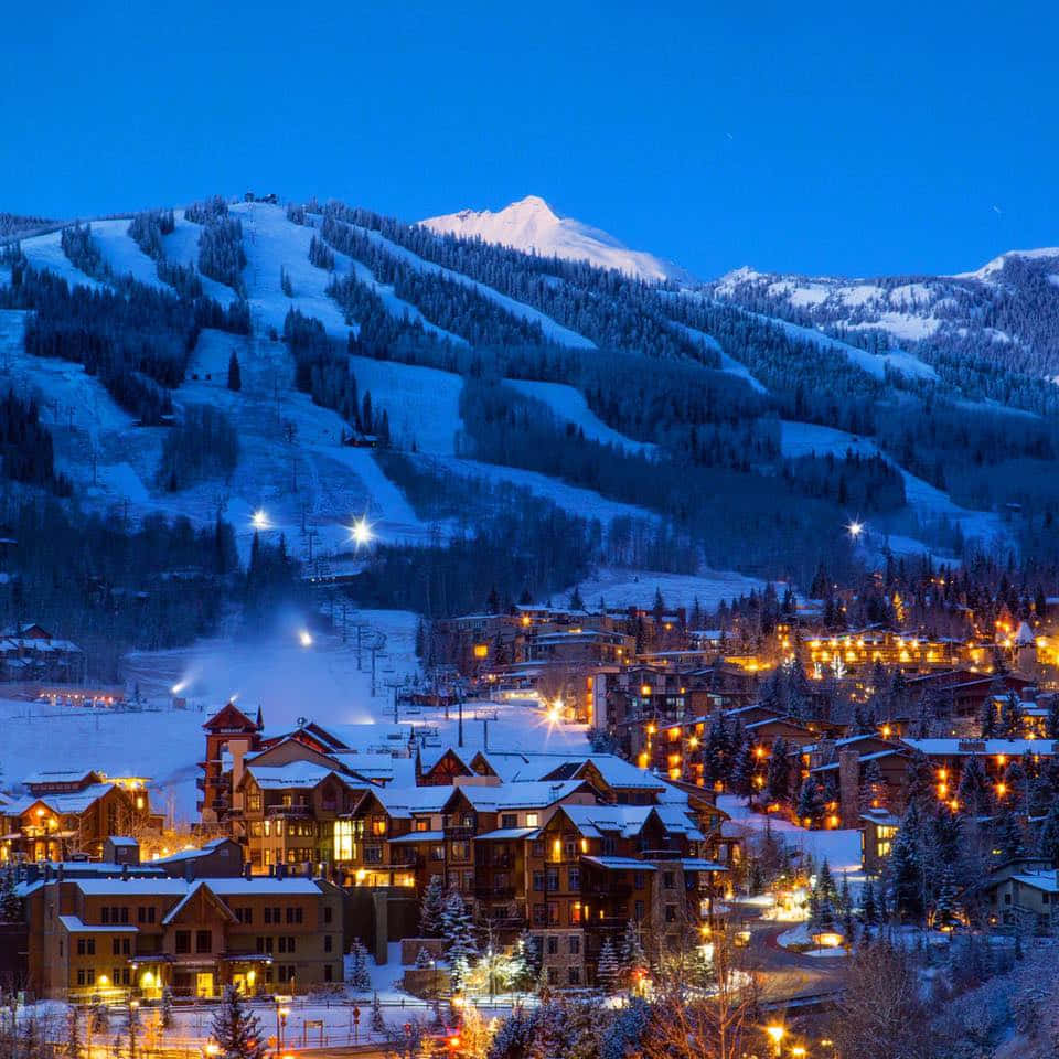 Colorado 桌布 壁紙 — 白雪覆蓋的山村在深藍色的暮色天空中閃爍著溫暖的燈光。