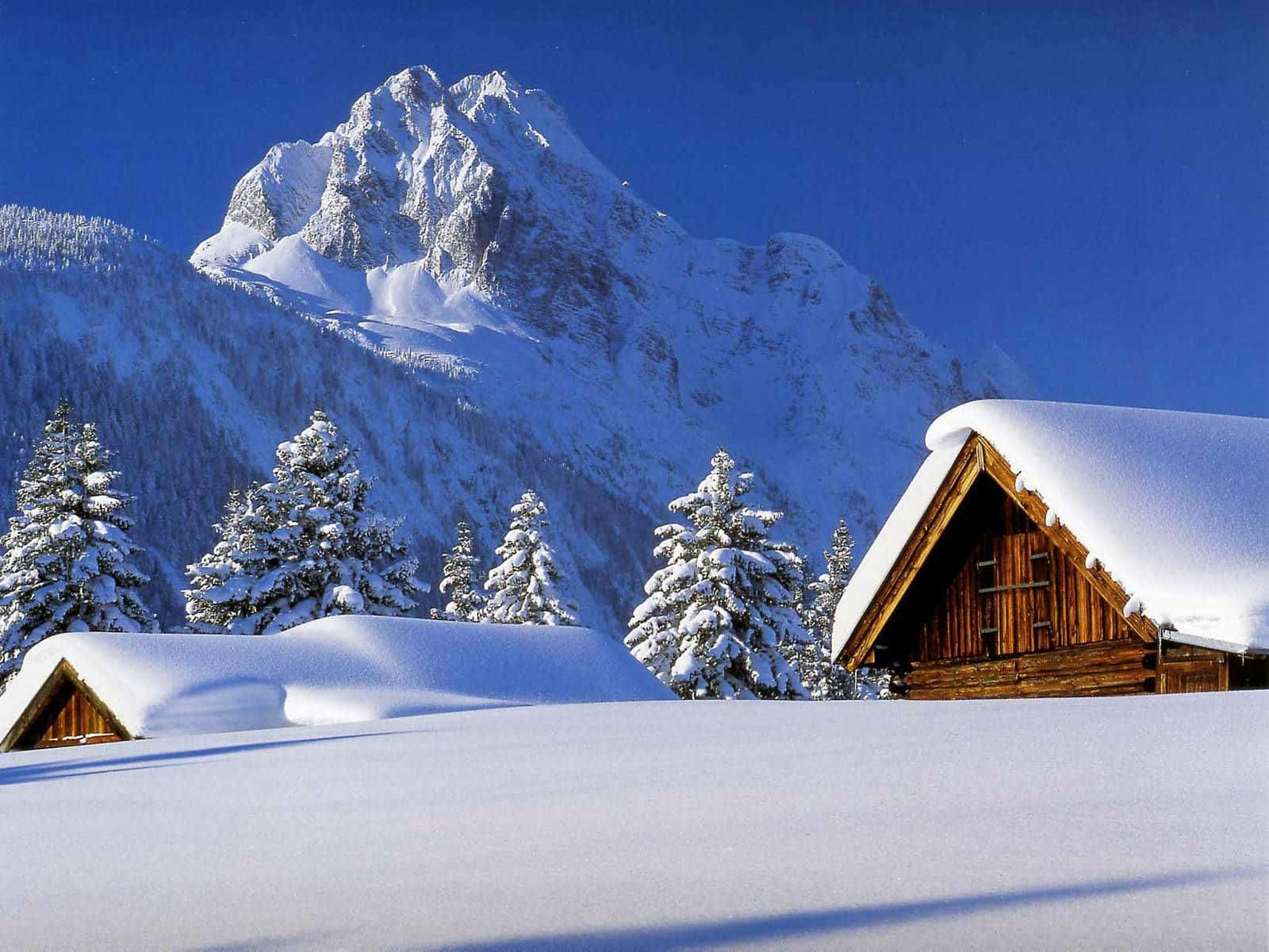 冬天桌面 桌布 壁紙 — 白雪覆蓋的木屋坐落在寧靜的冬季山谷中，天空湛藍清澈。