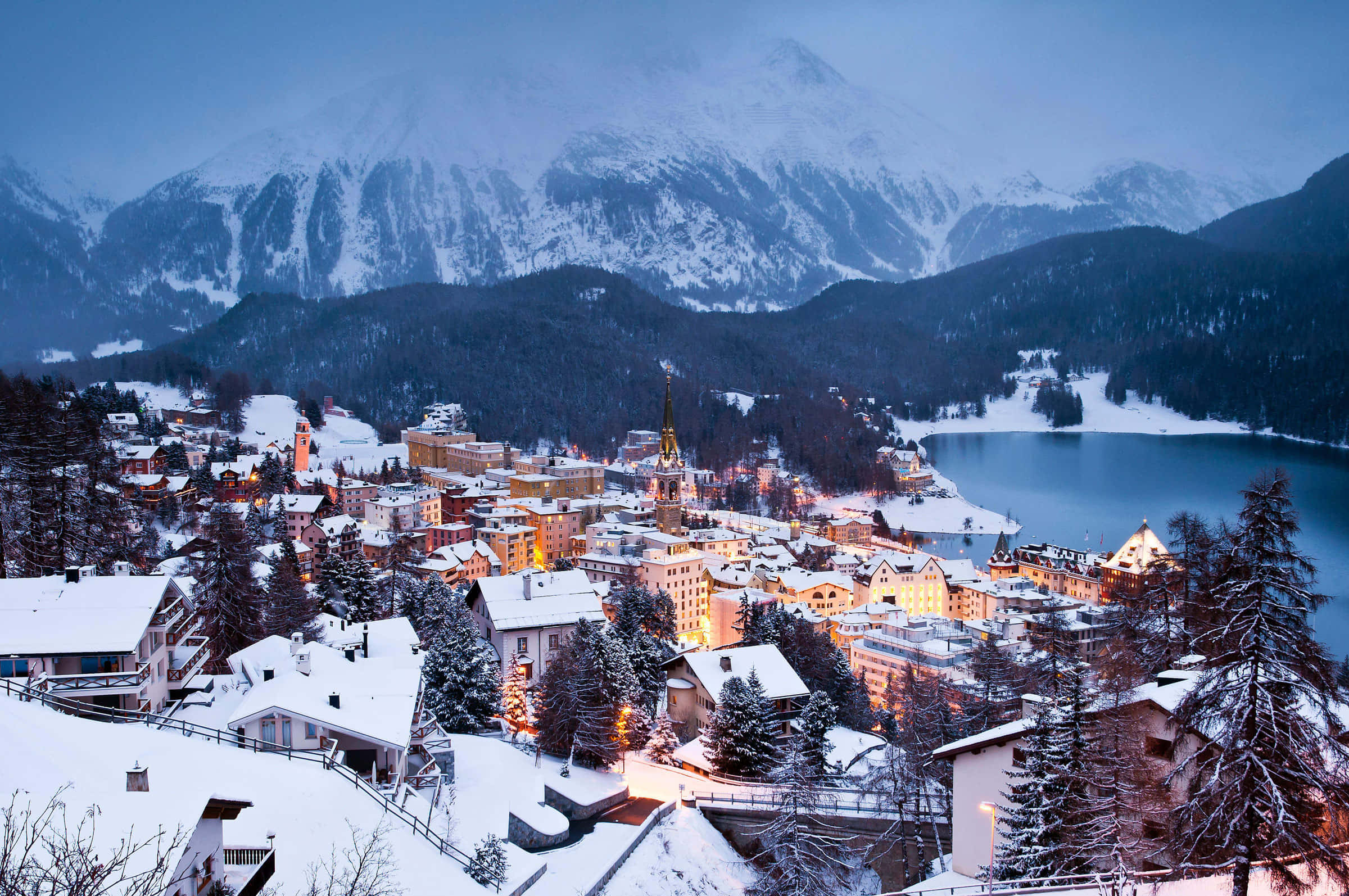 Switzerland 桌布 壁紙 — 白雪覆蓋著一個坐落在冰凍湖邊、在暮色天空下的舒適山城。