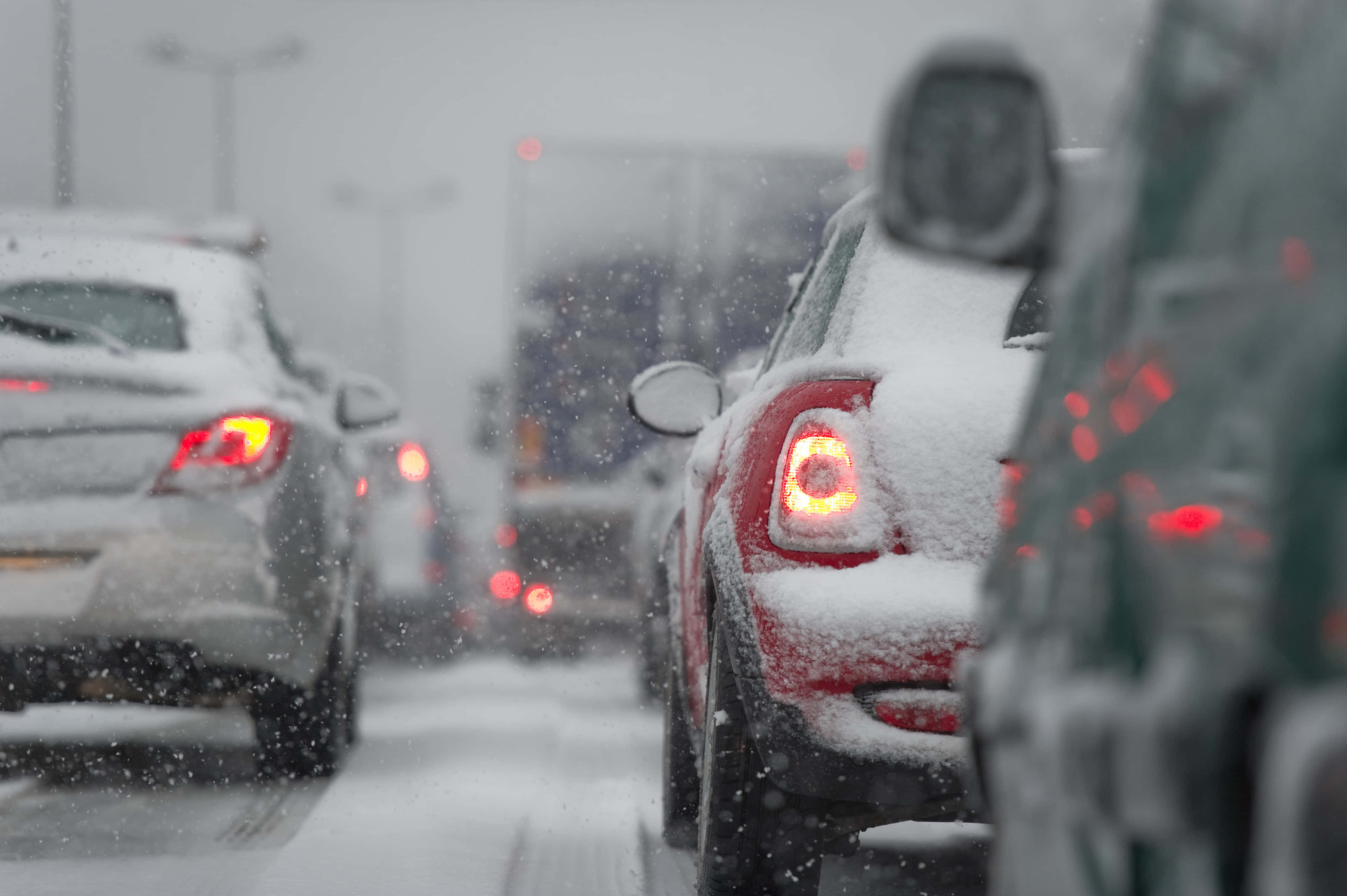Winter Driving 桌布 壁紙 — 白雪覆蓋著冰封交通堵塞中的汽車，紅色尾燈透過飄落的雪花閃爍。