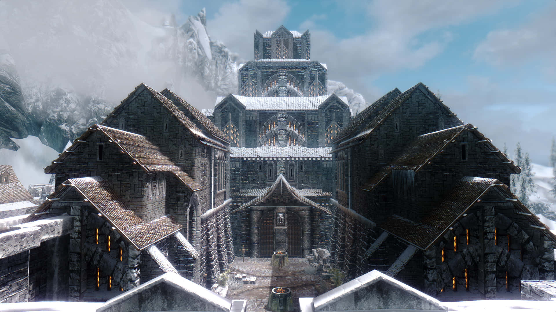 Skyrim Windhelm 桌布 壁紙 — 白雪覆蓋著古老的石建築和一座高聳的大教堂，位於多雲天空下冰封的山村。