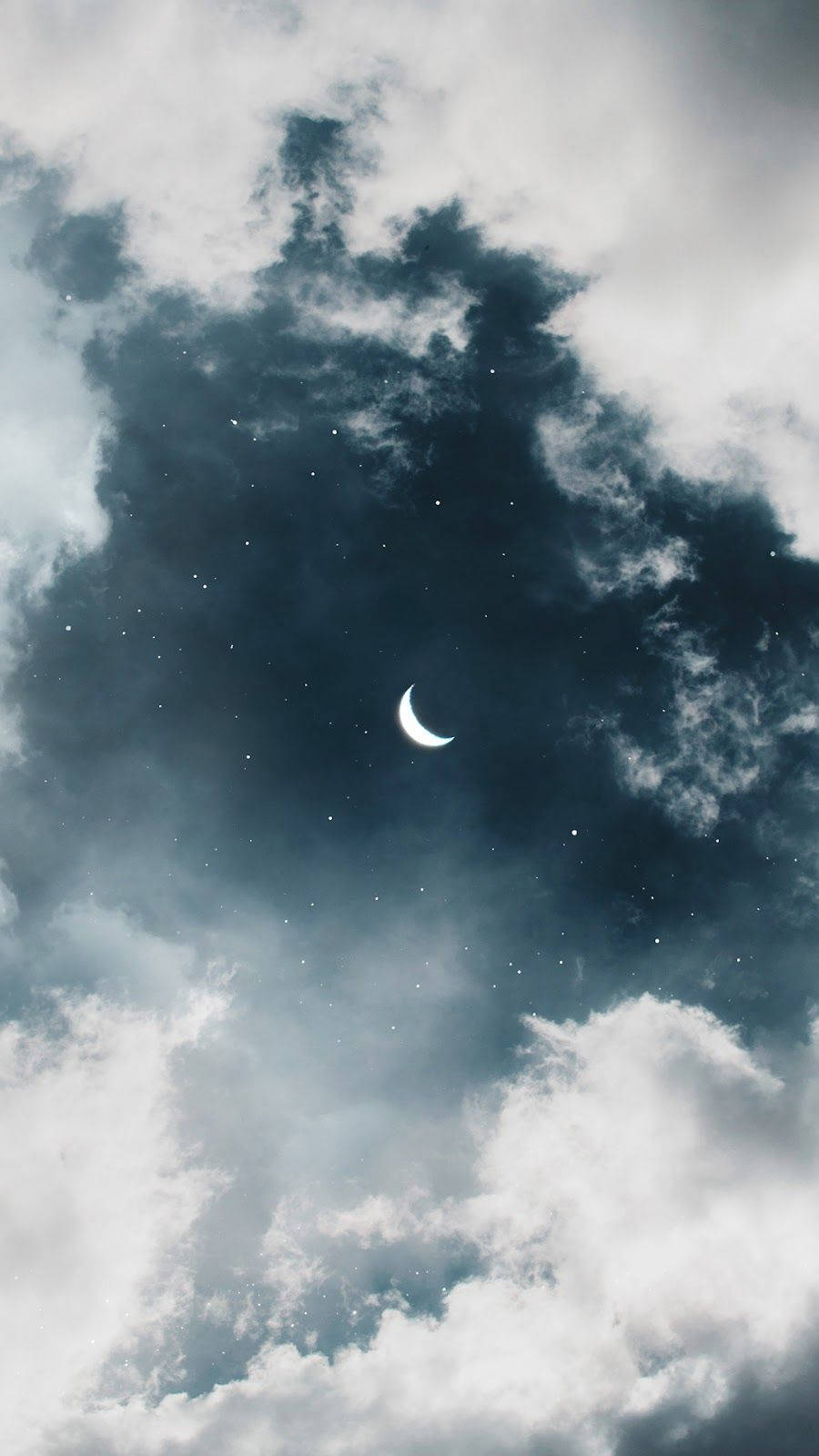新月穿過雲層和星星在黑暗的夜空中閃耀。