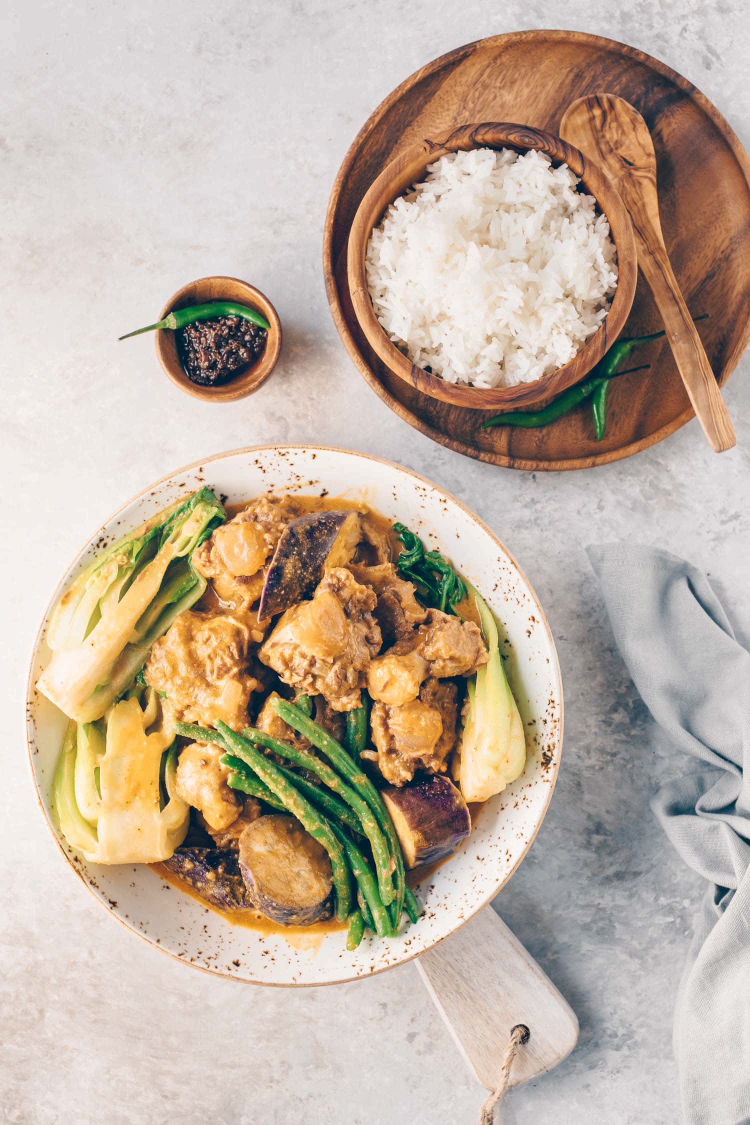 白飯、蝦醬與咖喱牛尾湯套餐 壁紙 — 一款奶油雞肉青豆咖喱，盛載於斑點鍋中，配以木碗白飯和辣椒醬。