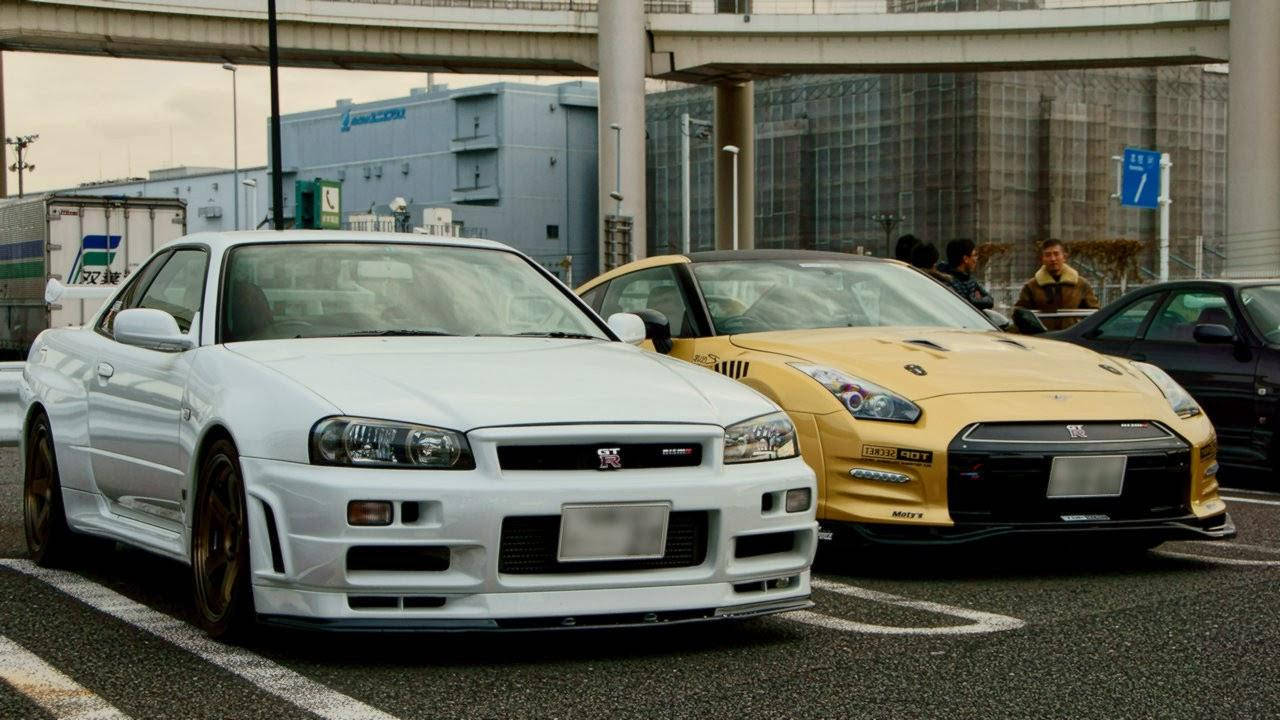 兩輛改裝的日產Skyline GT-R跑車停在天橋下的城市街道上。