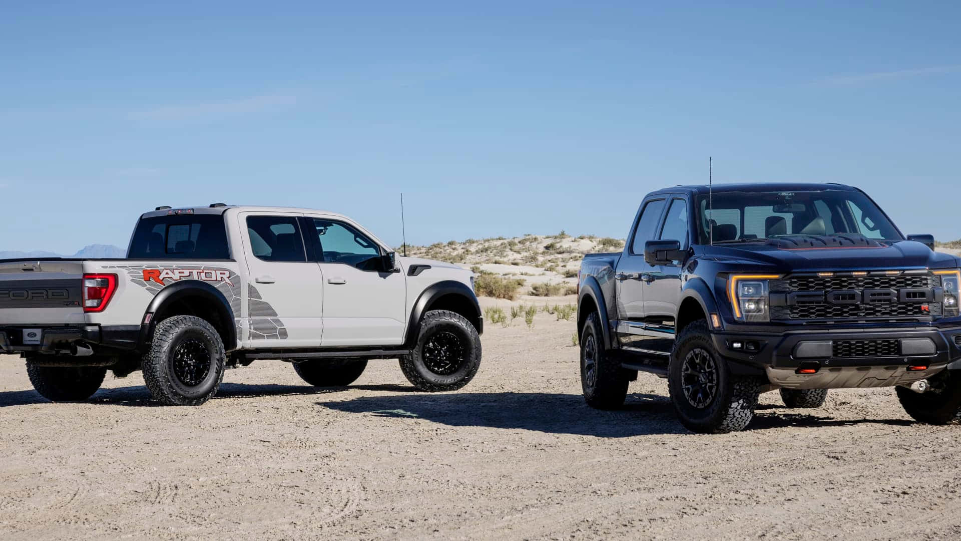 兩輛福特 Raptor 卡車停在沙漠中，夕陽西下。