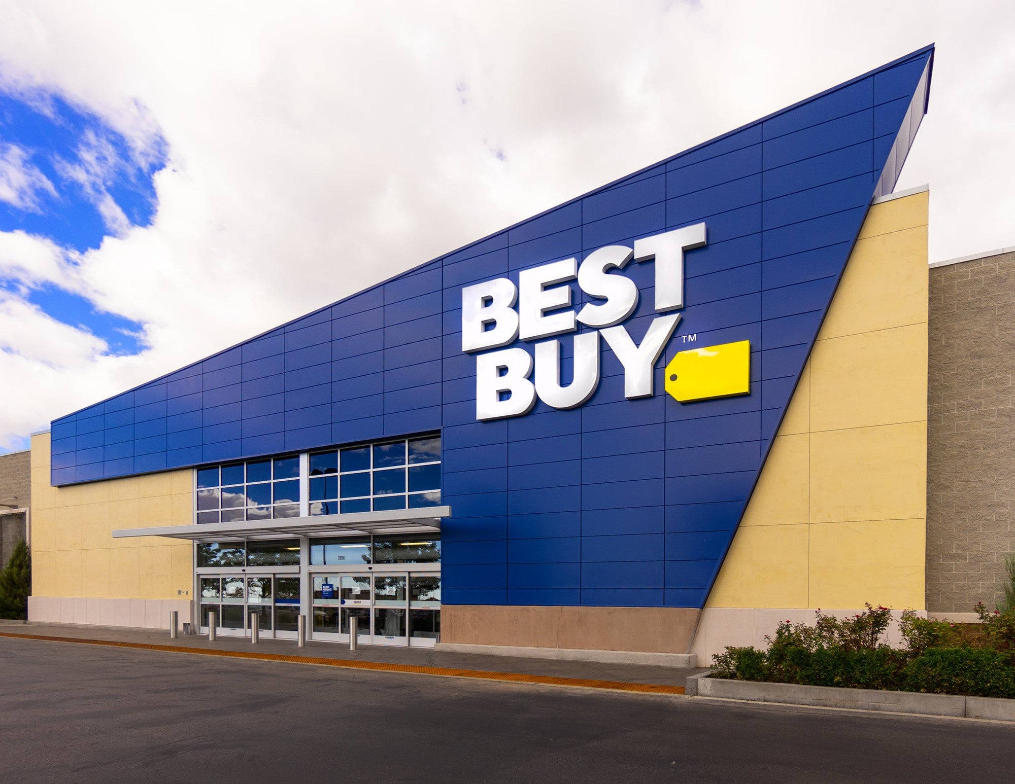 百思 buy 建築設計 壁紙 — 一間現代化的Best Buy商店，在部分多雲的天空下，有醒目的藍色和黃色標誌。