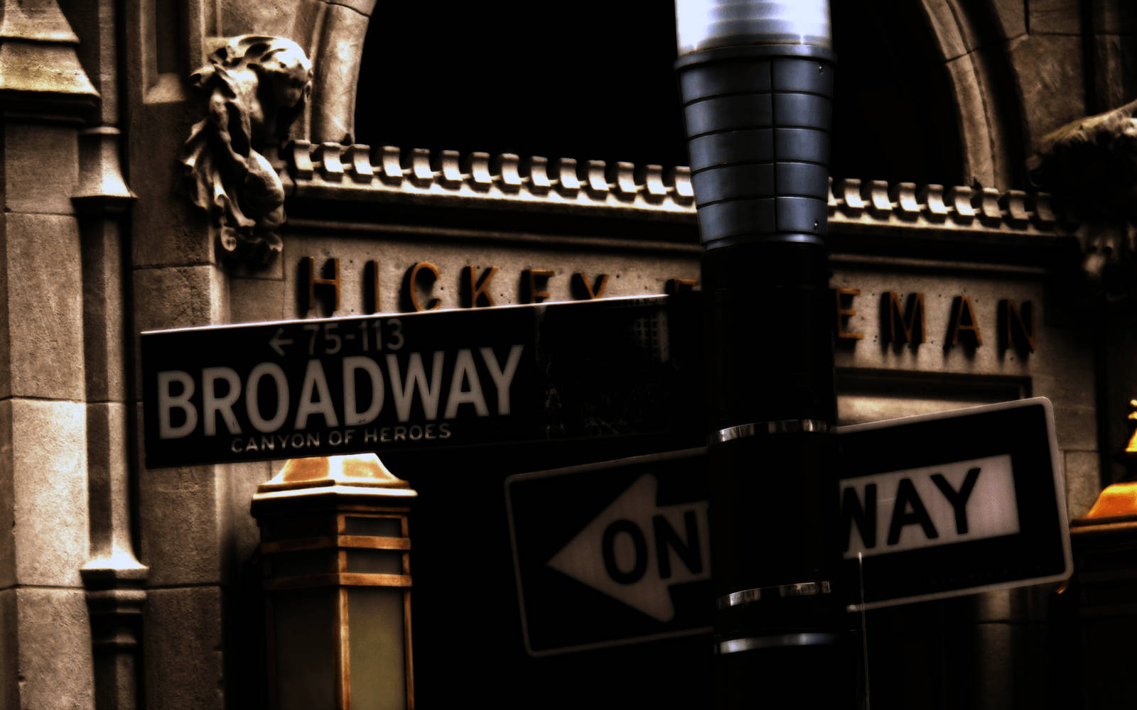 夜晚的 Broadway 街道標誌，石頭建築上有單向箭頭。