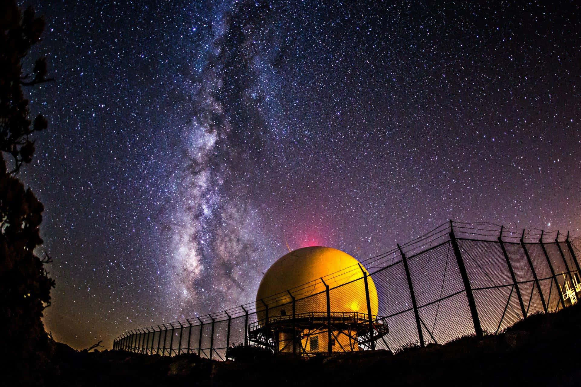 一個黃色雷達圓頂在星空下，銀河清晰可見。