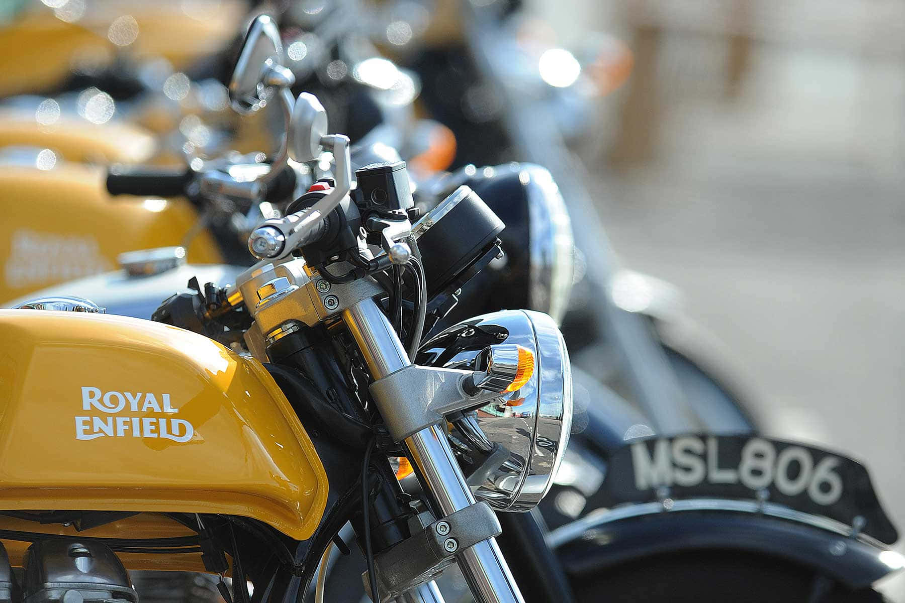 黃色 Royal Enfield 電單車，焦點在鍍鉻把手和頭燈上。