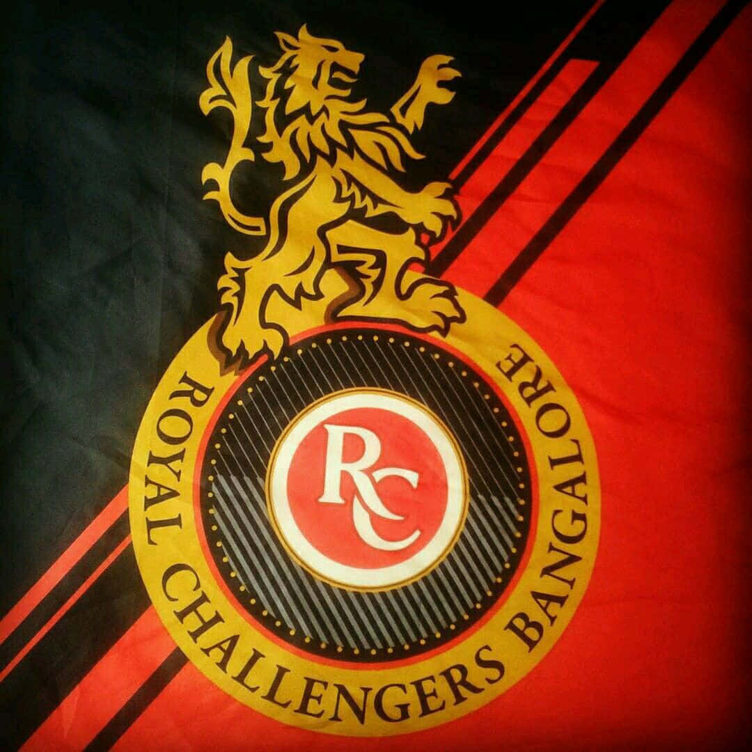 Rcb 桌布 壁紙 — 皇家挑戰者班加羅爾體育隊旗的特寫，旗幟上有一隻金色躍獅位於圓形徽章之上，布料為紅黑條紋。
