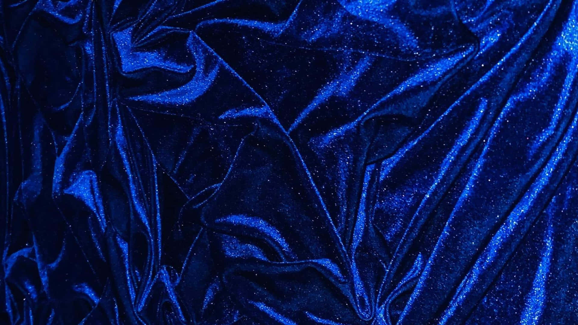 皇家藍絨布質感背景 壁紙 — 豐富的皇家藍色天鵝絨布料，在戲劇性燈光下呈現閃爍質感和深層皺褶。