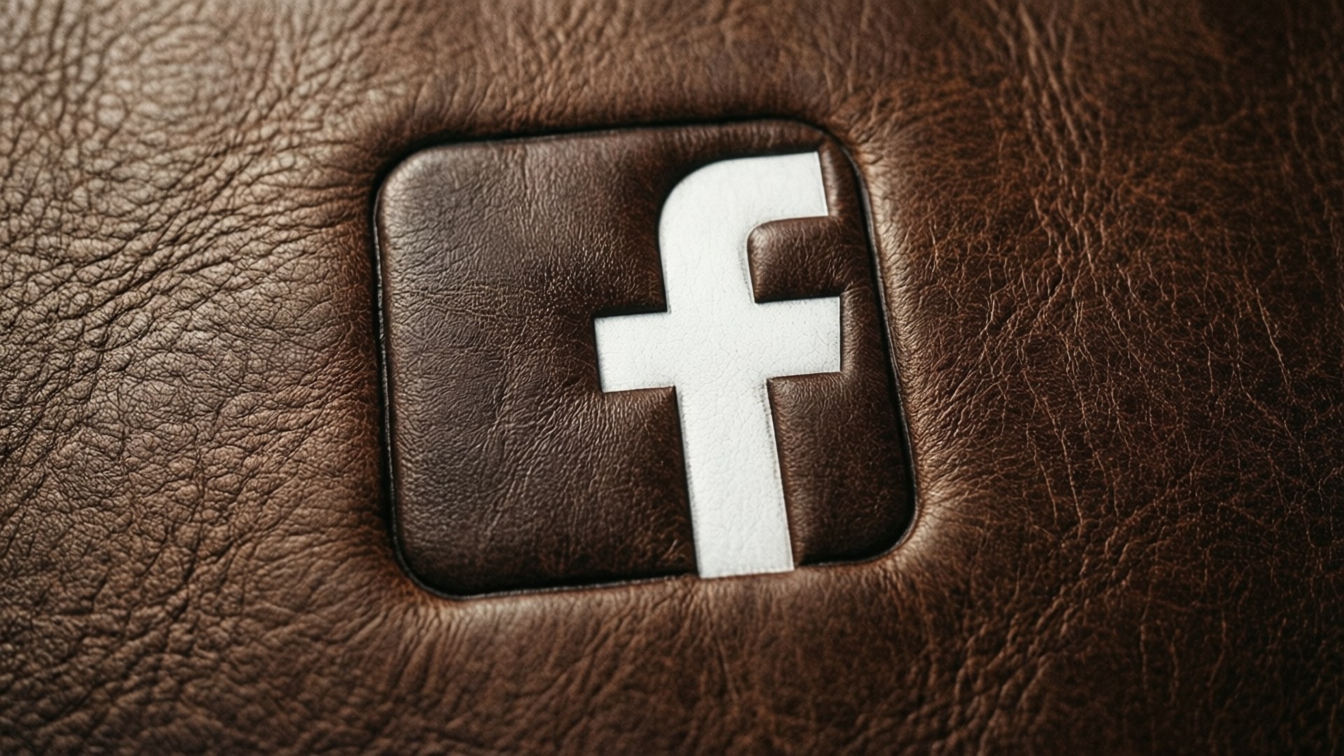 Facebook標誌壓印在棕色皮革表面，紋理清晰可見。