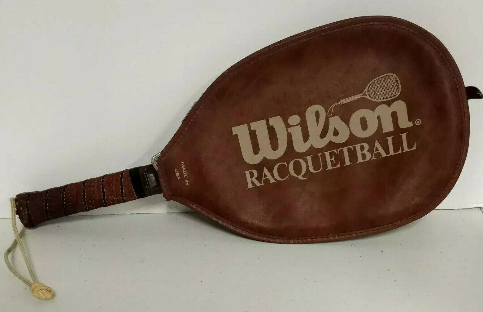 皮革握把壁球拍與皮革Wilson外套 壁紙 — 一個復古棕色皮革 Wilson 壁球拍靠在純白色背景上。