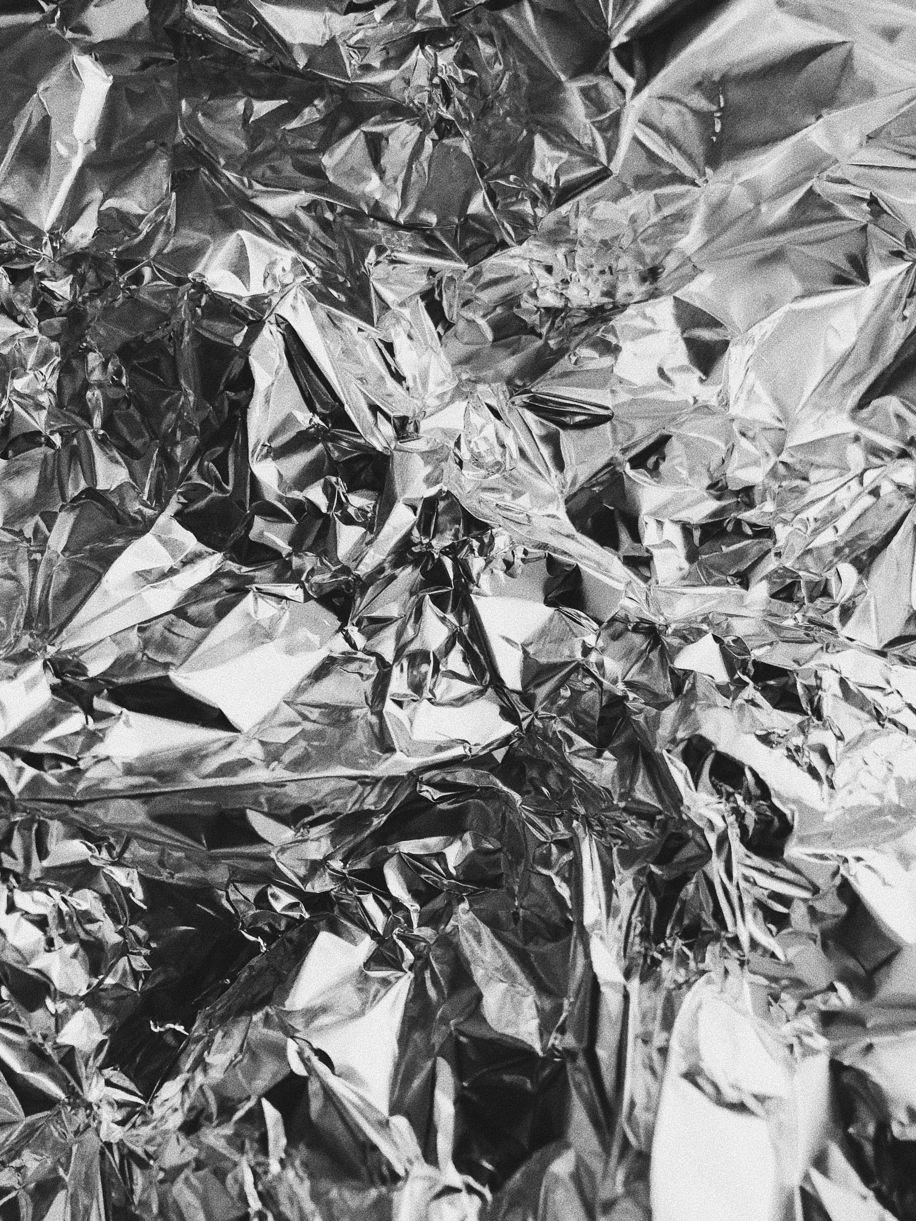 Foil 桌布 壁紙 — 皺巴巴鋁箔紙的特寫，帶有銳利的金屬高光和深色陰影，營造出紋理豐富的抽象表面。