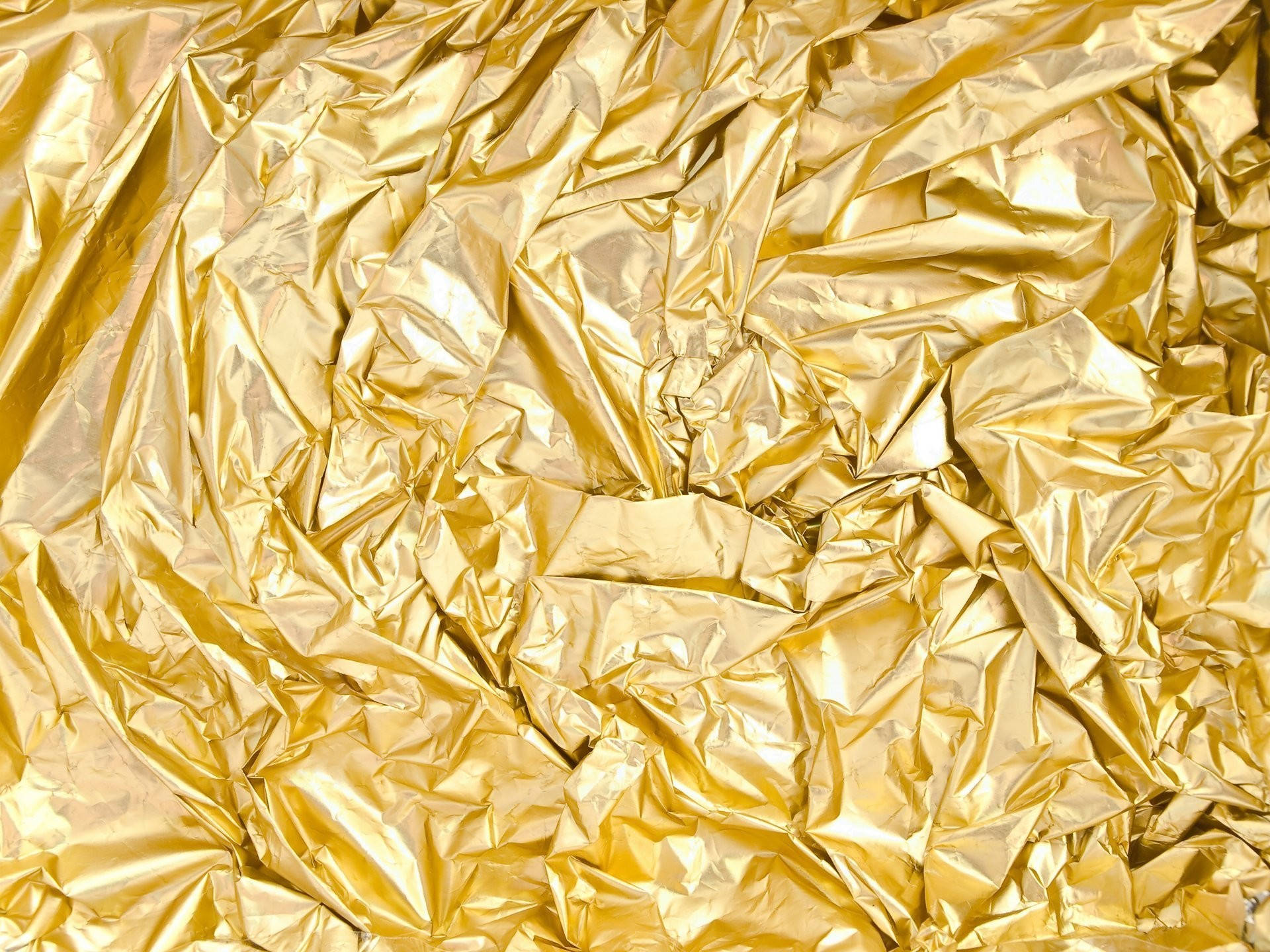 皺摺金箔 壁紙 — 皺巴巴的金箔特寫，帶有閃亮摺痕，在紋理圖案中反射光線。