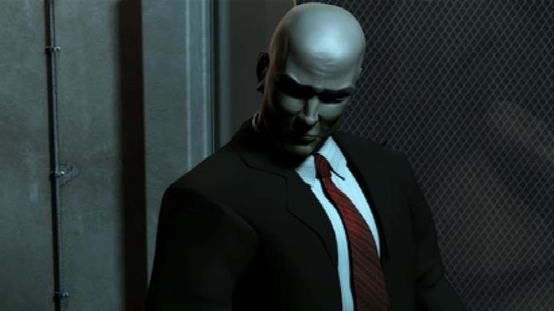 皺眉特工 HD Hitman 2 壁紙 — 一個光頭男子穿著深色西裝和紅色領帶，站在一個光線昏暗的工業環境中，身後有鐵絲網圍欄。