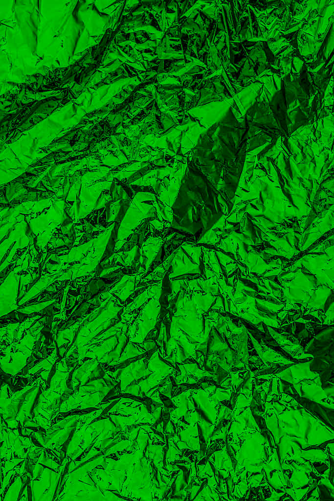 特寫皺紋綠色金屬箔紙，帶有銳利的摺痕和反射亮點。
