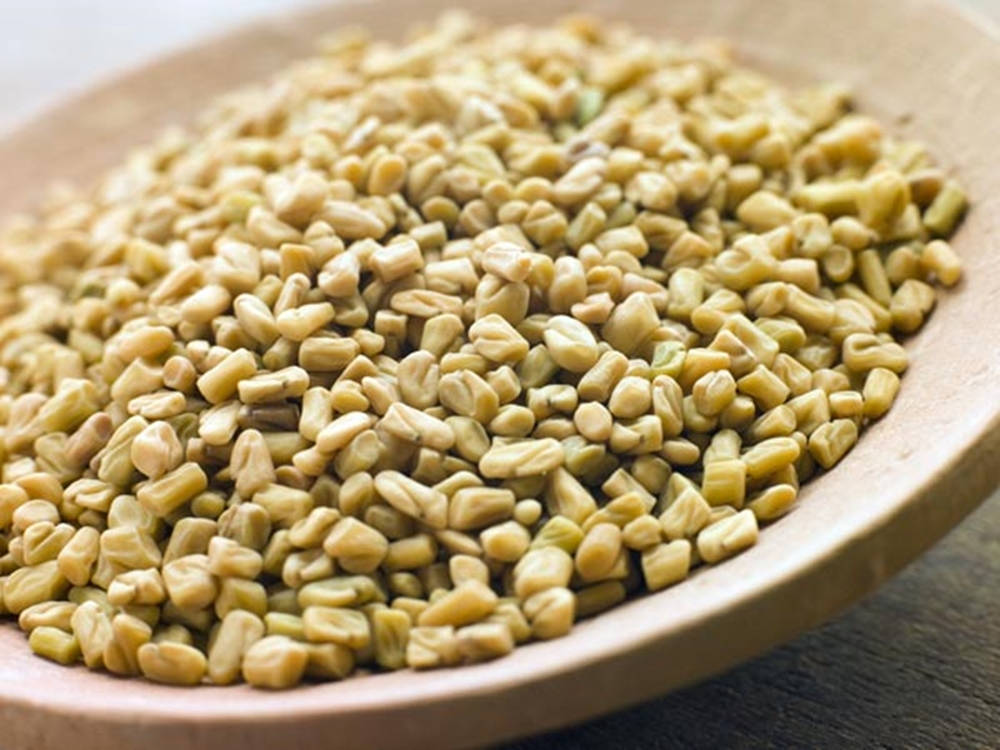 盛滿茴香籽的木盤 壁紙 — 特寫鏡頭：淺綠色葫蘆巴籽堆放在木碗中，柔和自然光照射。