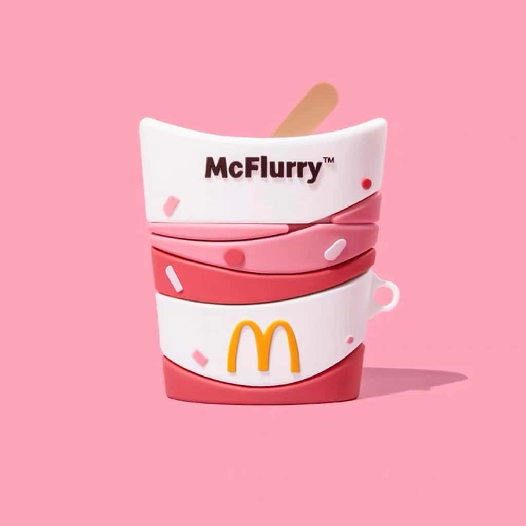 堆疊的McFlurry杯玩具，帶有粉紅色漩渦和木勺，置於粉紅色背景上。