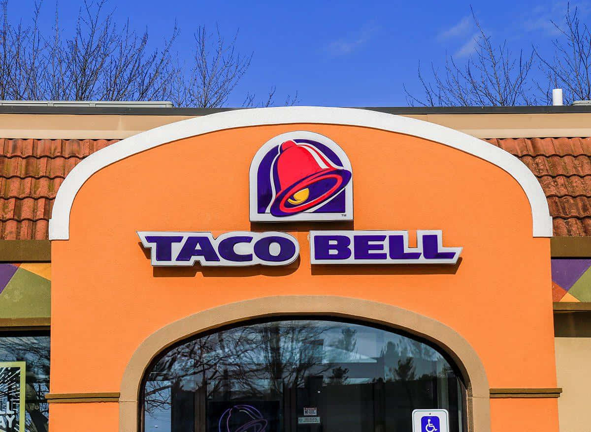 Taco Bell餐廳入口，橙色牆壁配藍天背景。