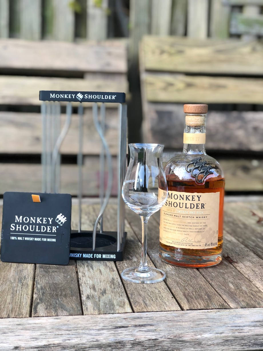 Monkey Shoulder威士忌瓶和品酒杯在戶外木桌上。