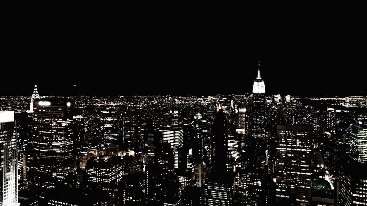 盡情享受紐約市的美景！ 壁紙 — 紐約市夜晚的高對比度黑白航拍圖，帝國大廈在無數燈火通明的摩天大樓中閃耀著明亮的光芒。