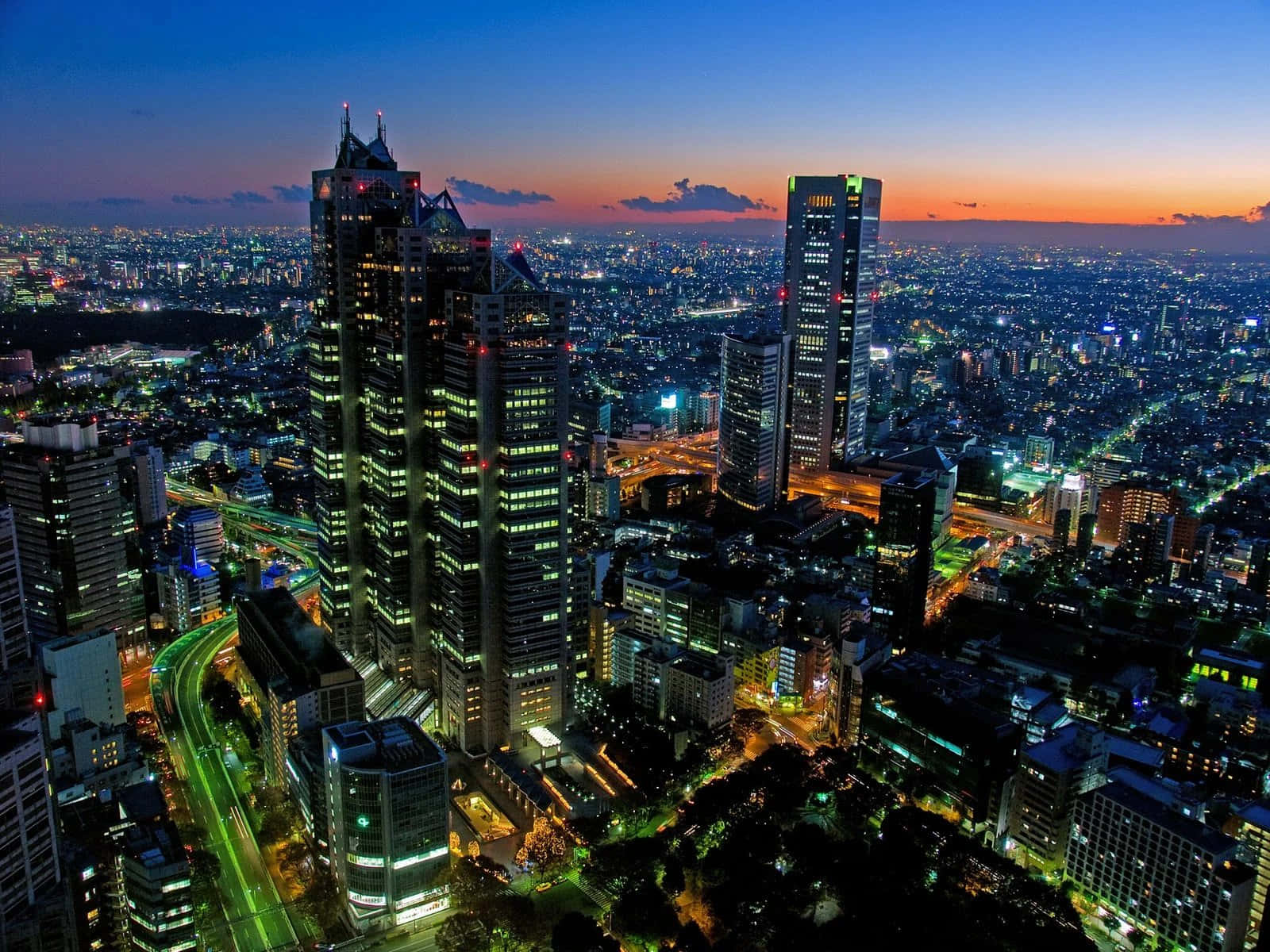 黃昏時分的城市天際線，燈火通明的摩天大樓和發光的街道。