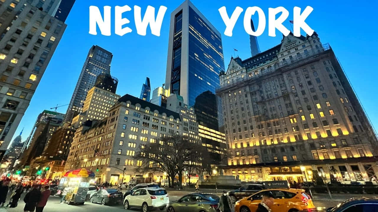 盡覽紐約市的輝煌風采 壁紙 — 黃昏時分充滿活力的紐約市街道，下方有燈火通明的摩天大樓和繁忙的黃色出租車。