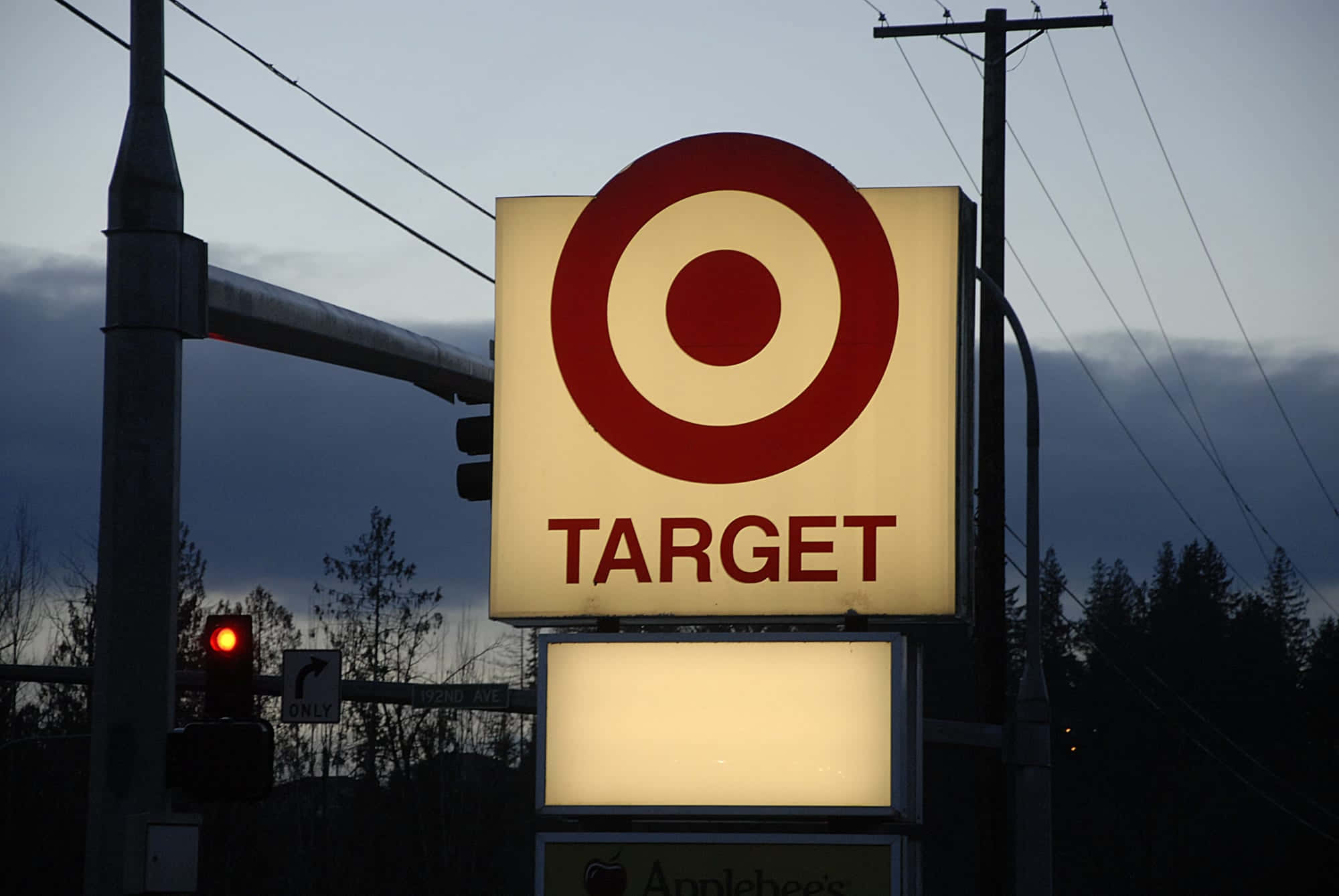 Target商店標誌在黃昏時分亮起，伴隨交通燈和樹木。