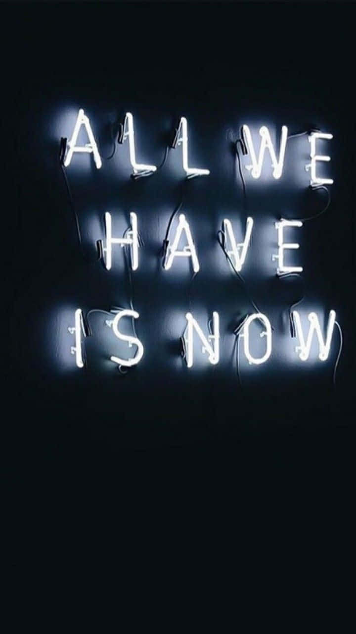 霓虹招牌在黑色牆壁上以白色顯示「ALL WE HAVE IS NOW」。