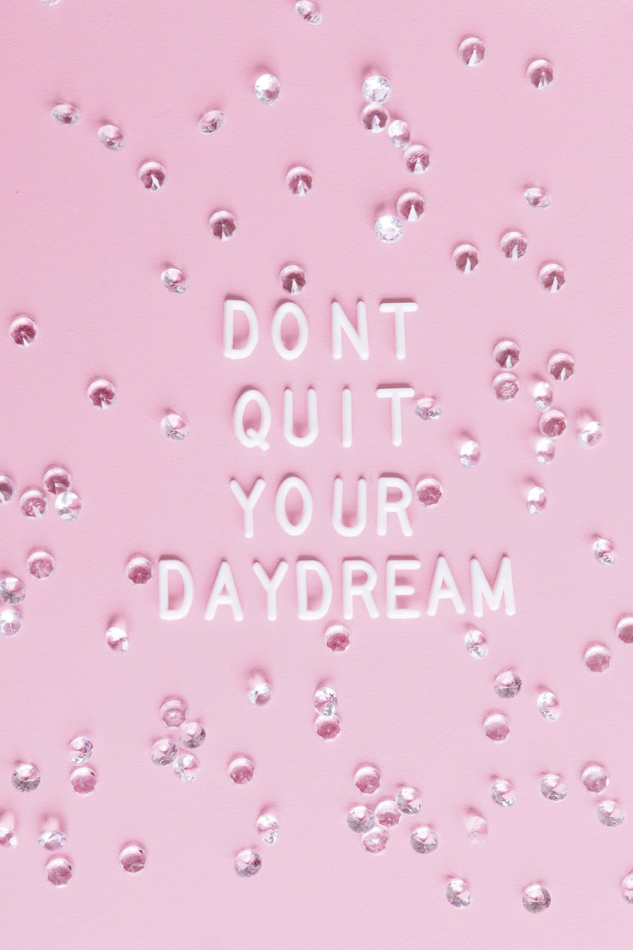 看看你走過多遠，你一定能做到！ 壁紙 — 白色3D字母拼出「DON'T QUIT YOUR DAYDREAM」，散落在柔軟的粉紅色表面上，點綴著閃亮的銀色水鑽。
