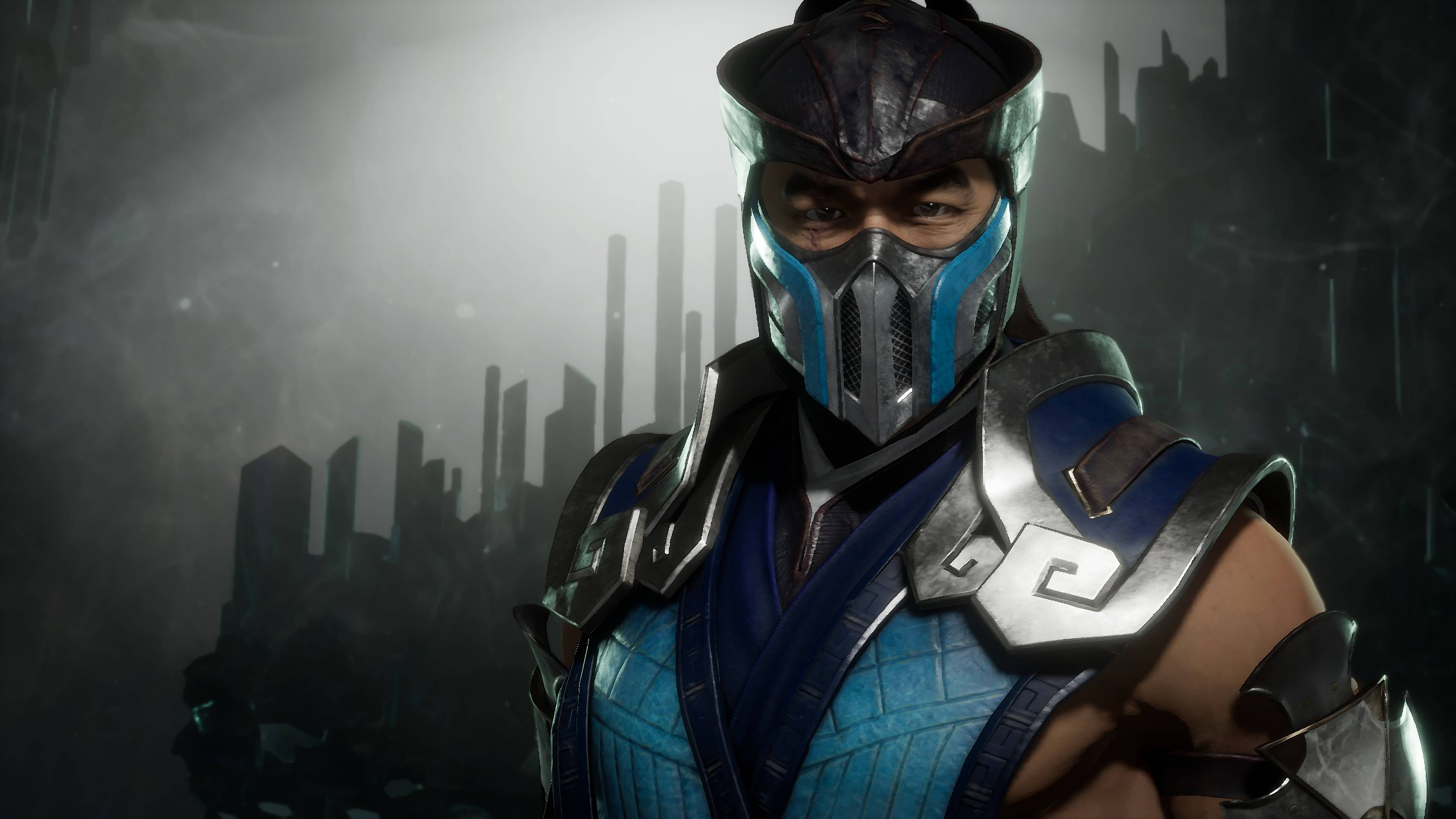 真人電影《 Mortal Kombat》Sub-Zero 3D封面 壁紙 — 一個戴著面具的戰士，身穿藍色和銀色盔甲，挑釁地站在霧氣瀰漫的未來城市天際線前。