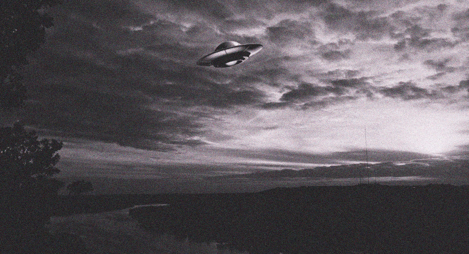 UFO在多雲天空下盤旋在黃昏的黑暗景觀之上。