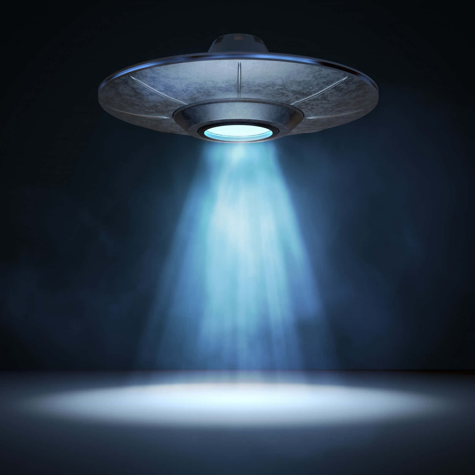 真實UFO黑暗中投射探照燈圖像 壁紙 — 一個金屬UFO在黑暗中盤旋，向反射地板發射明亮的藍色光束。