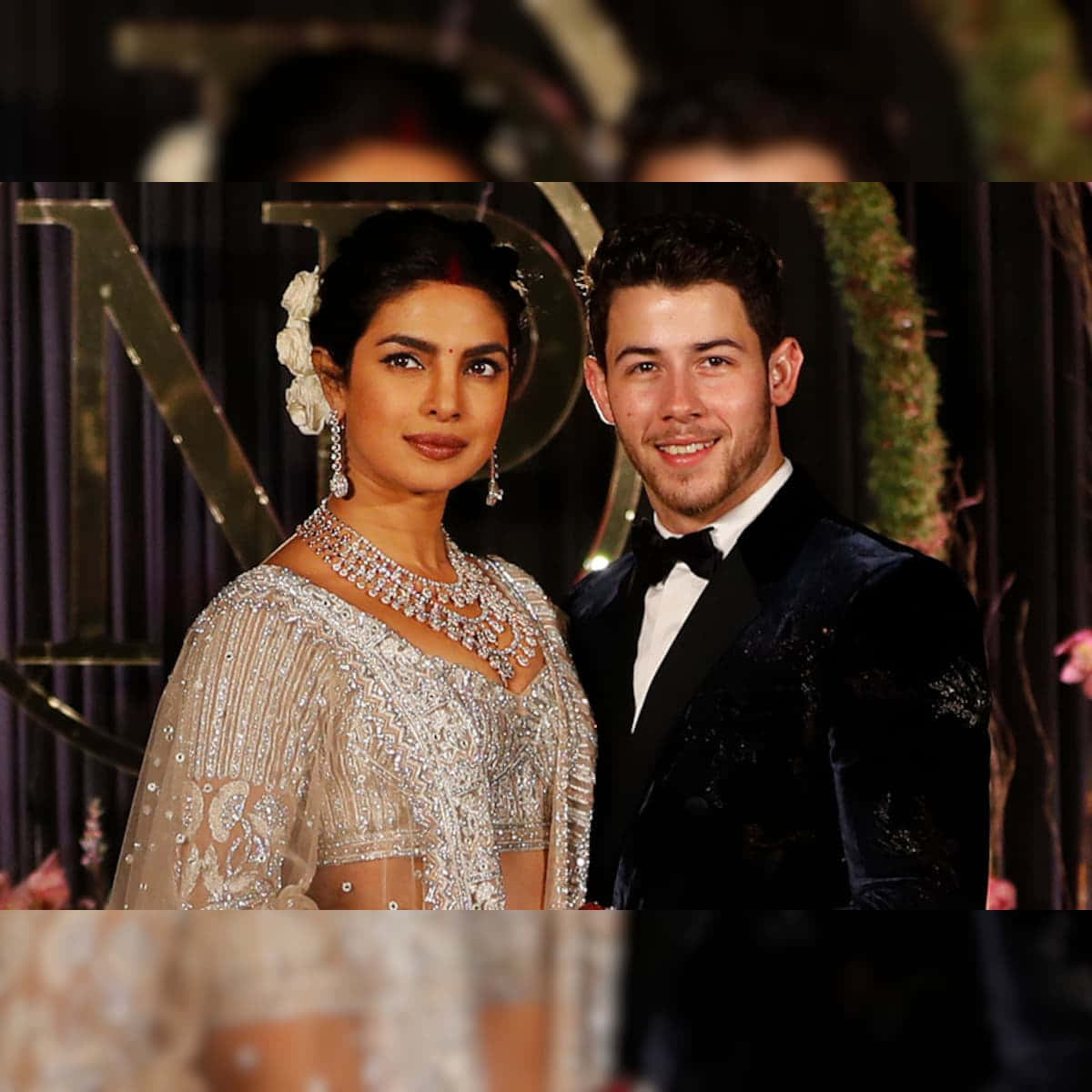 真愛的畫面 壁紙 — 一對魅力情侶在正式活動中合照，Priyanka Chopra 身穿閃亮銀色禮服，Nick Jonas 身穿天鵝絨燕尾服。