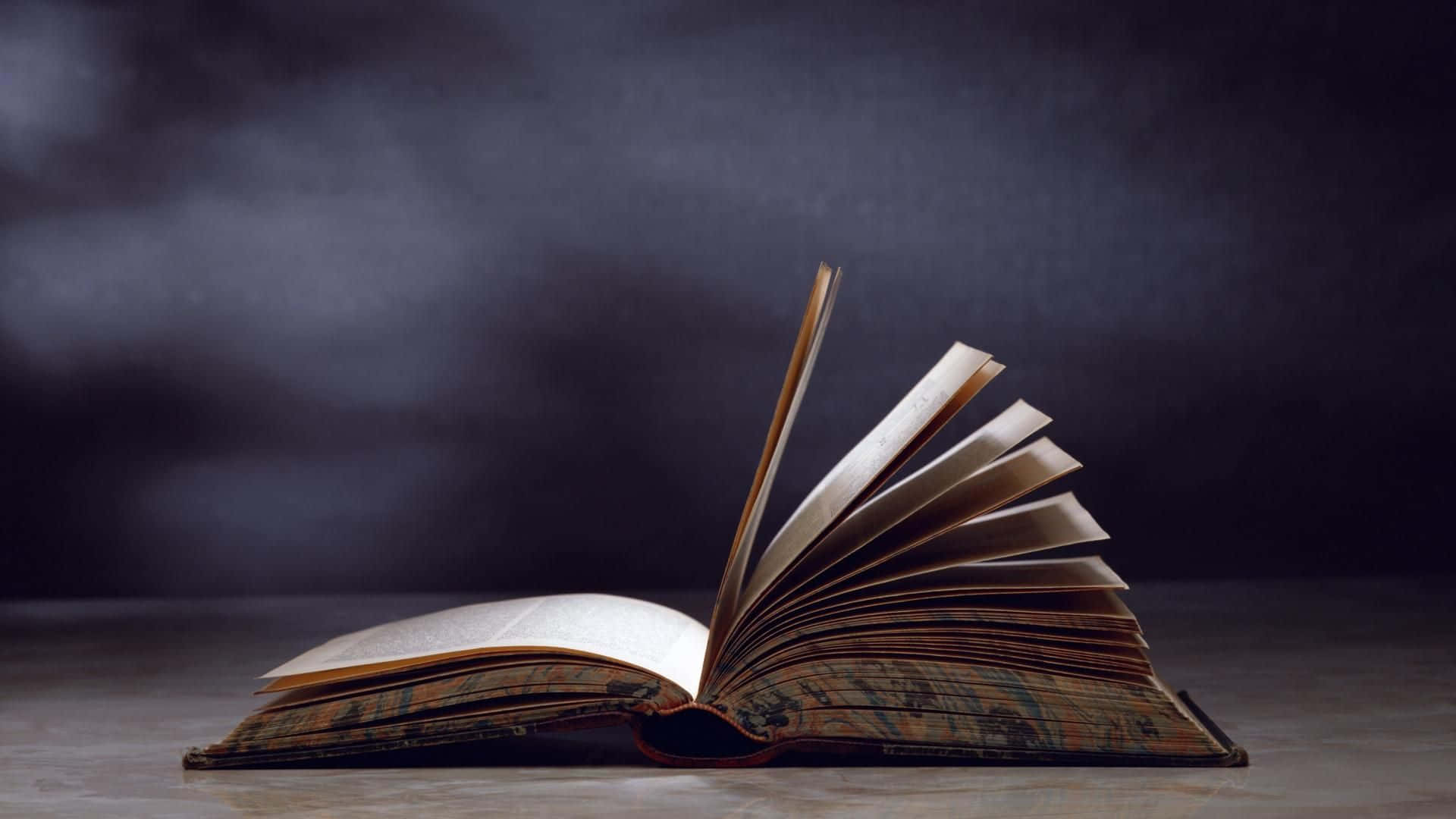 一本打開的復古書，書頁如扇般展開，放在樸素的表面上。