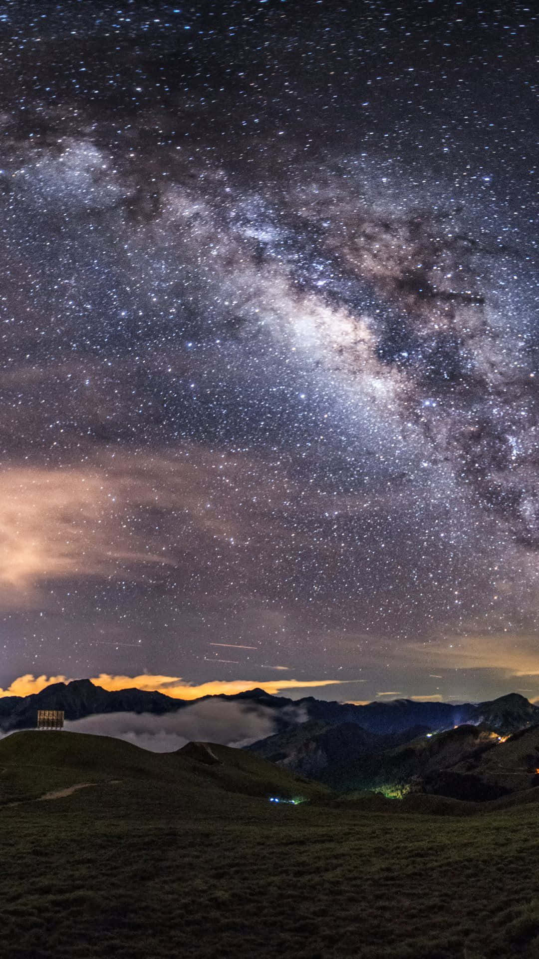 銀河系在山脈上方，夜晚有發光的雲層