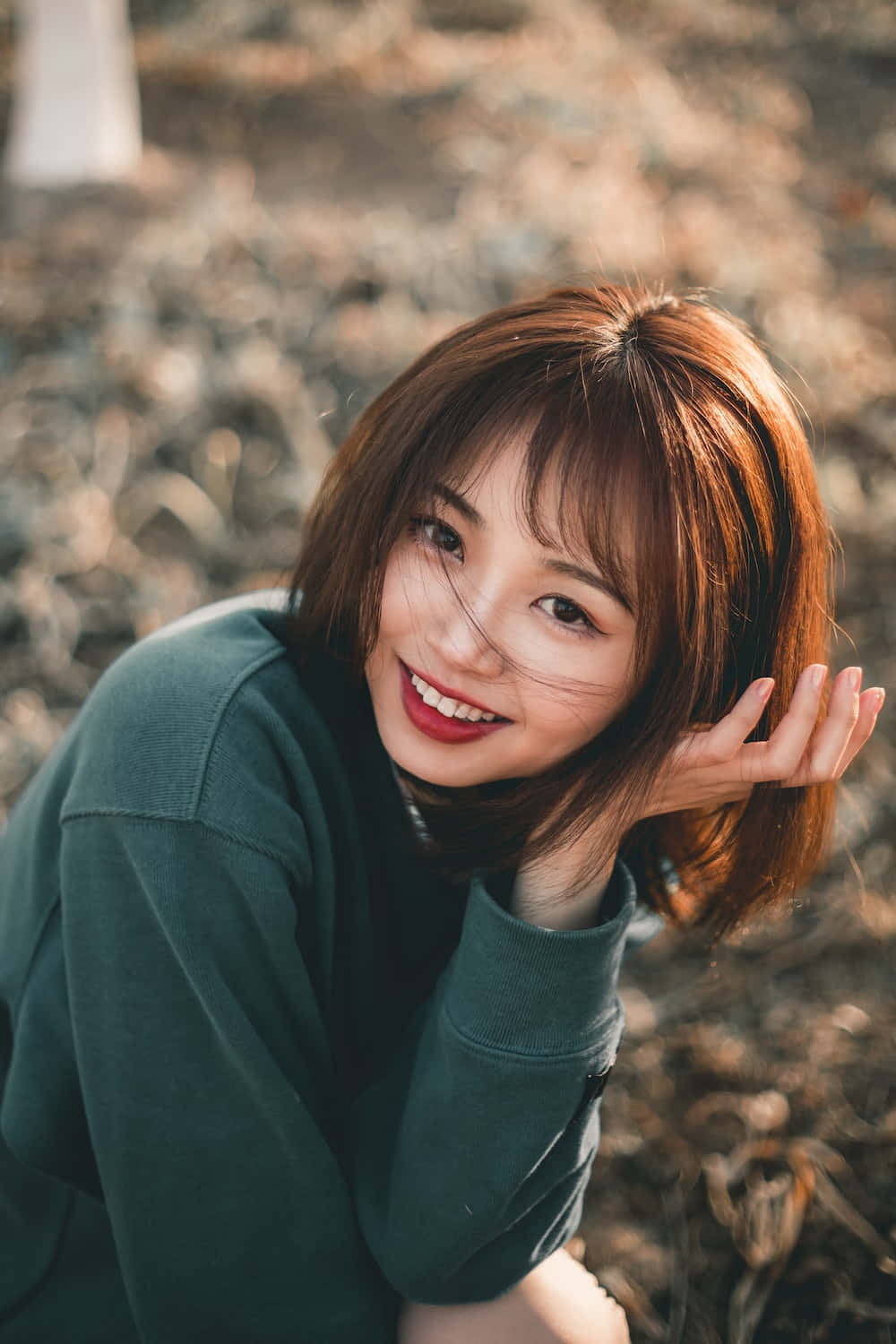 年輕女性在戶外微笑，手靠近臉部